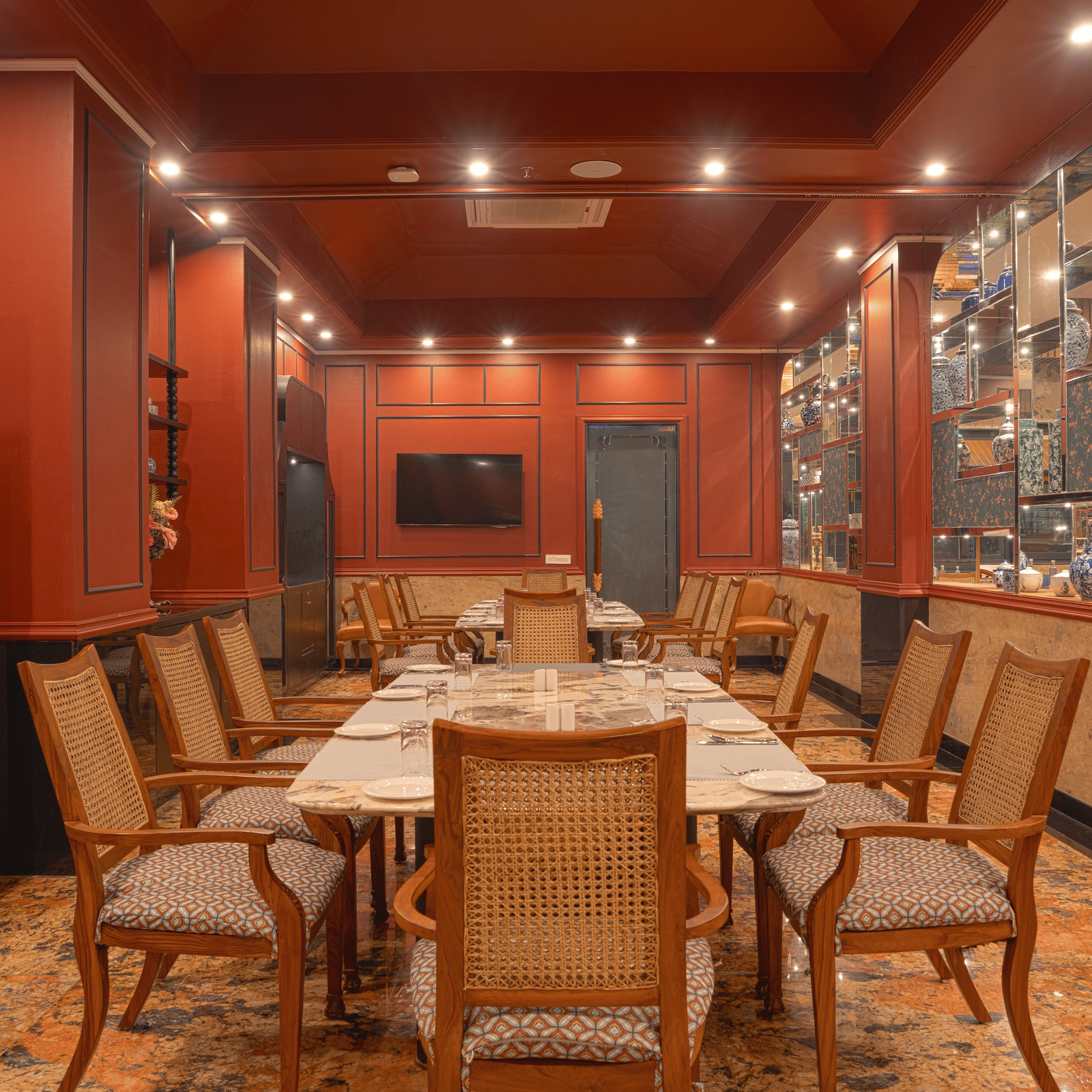 A dining room with a long wooden table set for a meal, surrounded by upholstered chairs and wood-panelled walls at MAYFAIR Bay Resort, Paradeep.