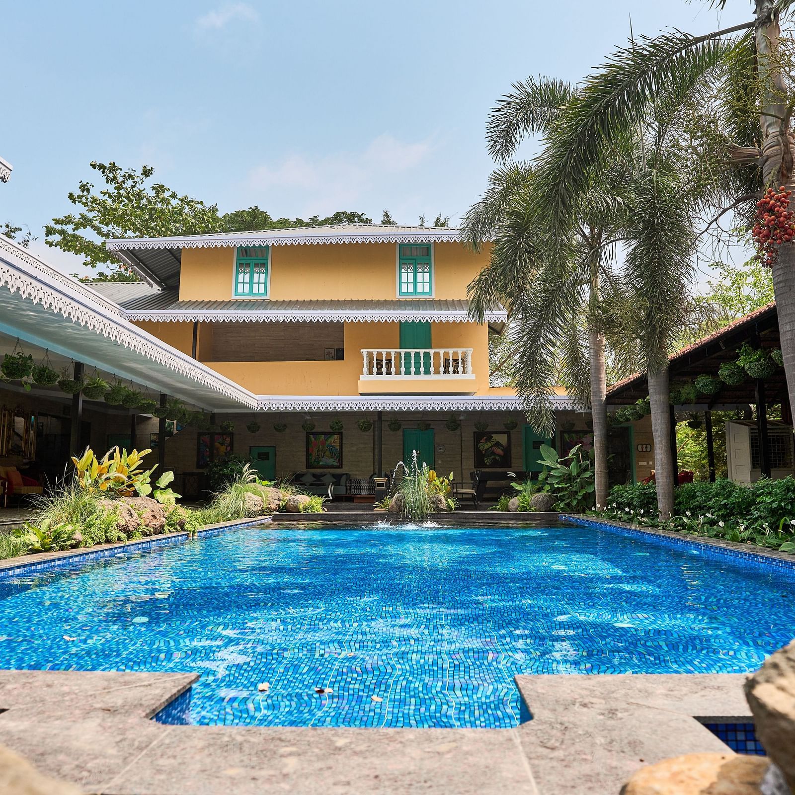 Swimming pool with a facade, surrounded by plants and trees at Mayfair Manor, Alibag