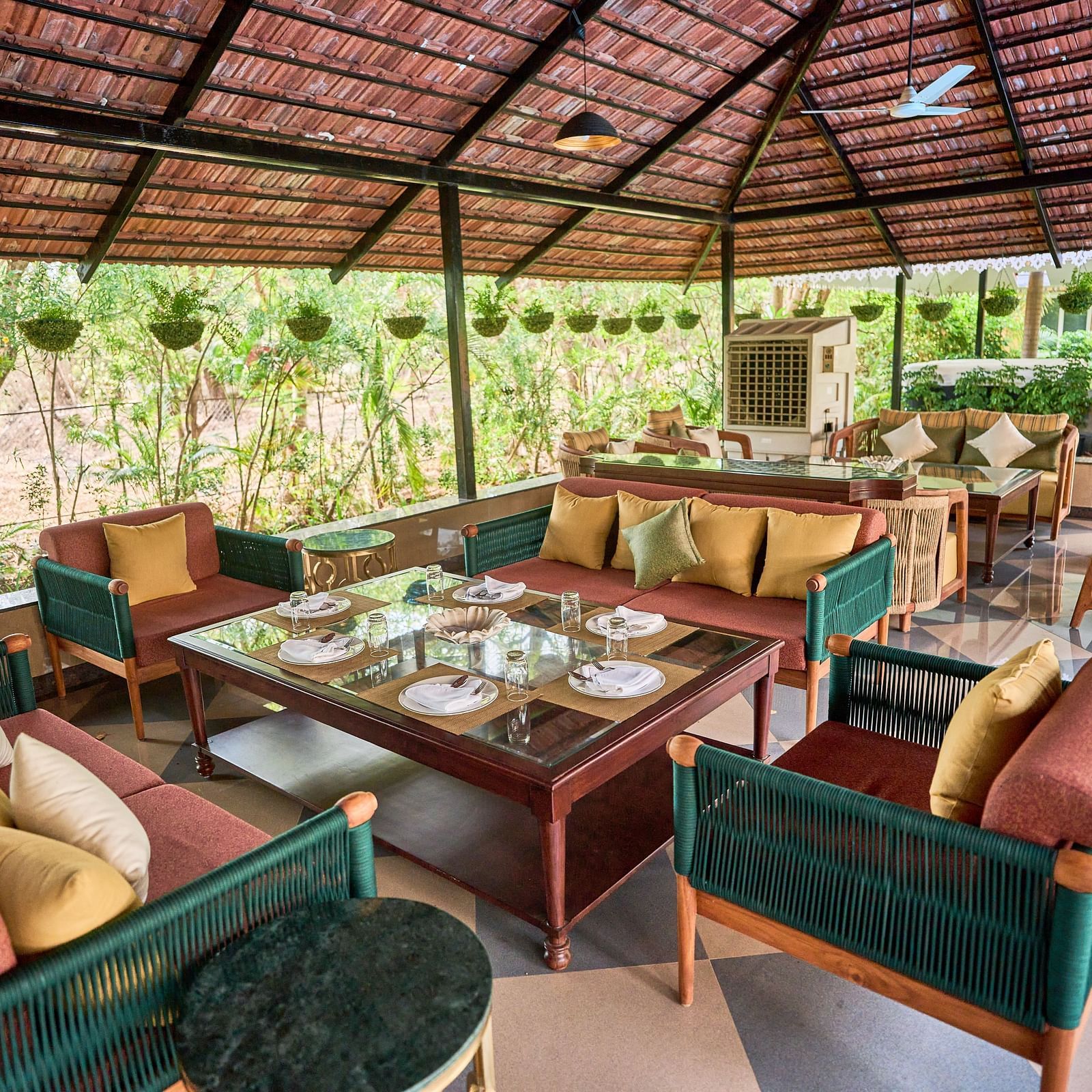 A cluster of cushioned sofas around the table, creating a lounging area at Mayfair Manor, Alibag