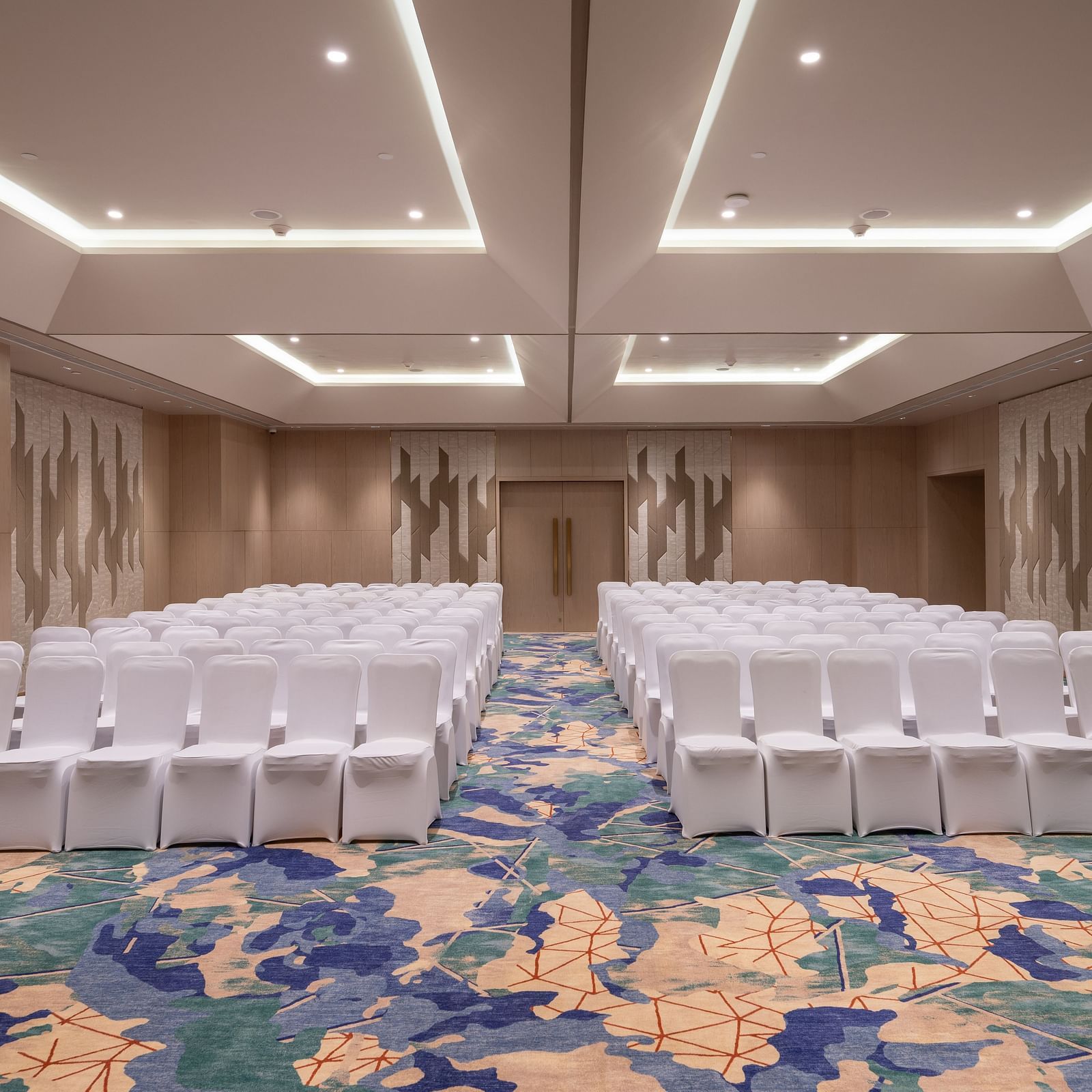 Theatre-style seating in a modern conference hall with patterned carpet at Merlis Hotel, Coimbatore.