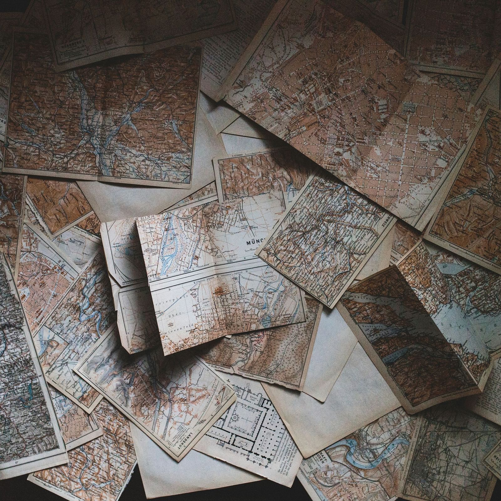 An array of old maps spread out on a surface, displaying intricate geographic details and historical regions, capturing the essence of exploration and discovery.