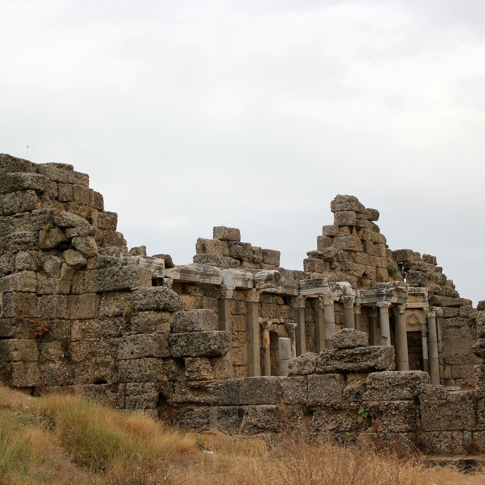 Ruins of an ancient stone structure standing against the cloudy sky