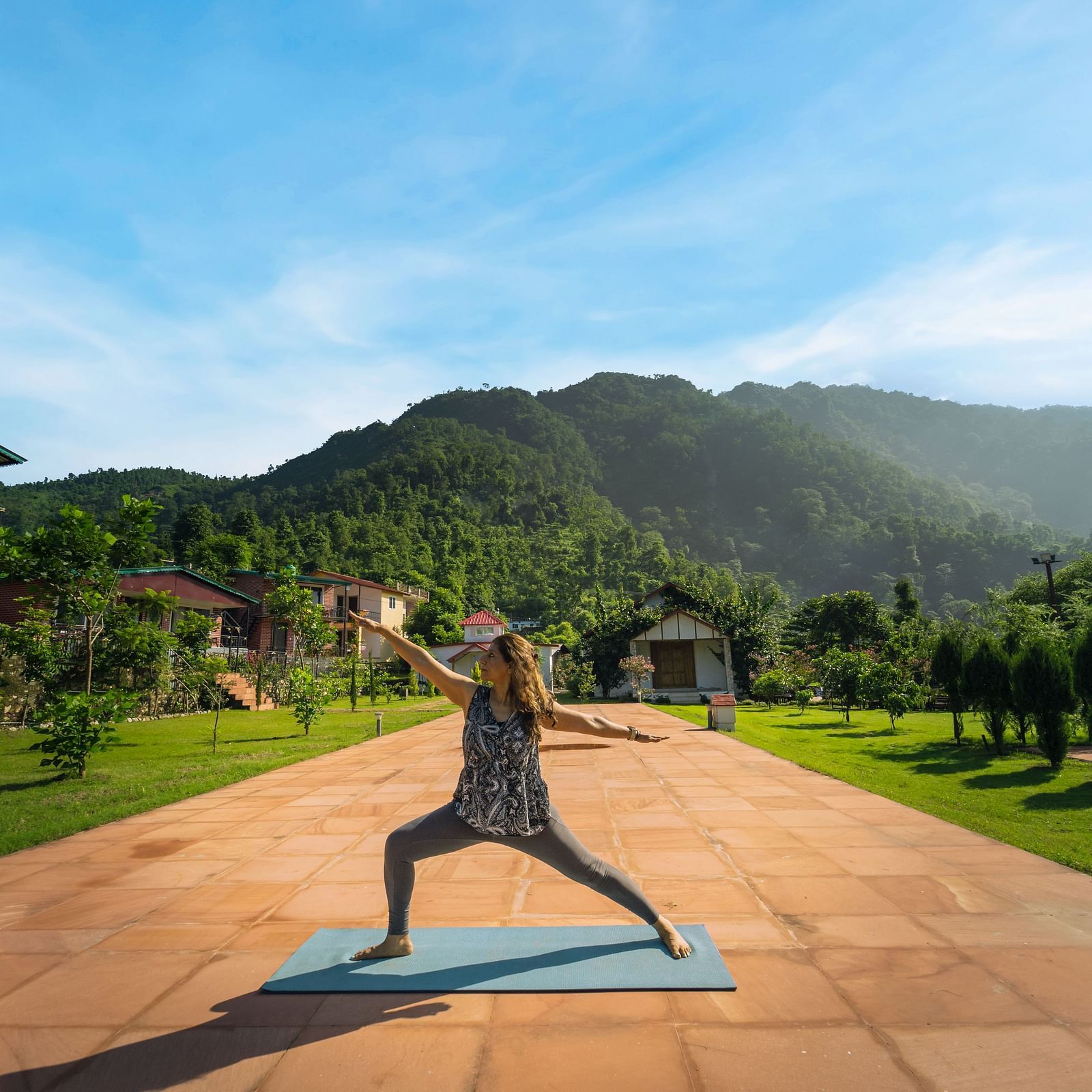 a road with a mountain view on the back with a lady doing a yoga pose