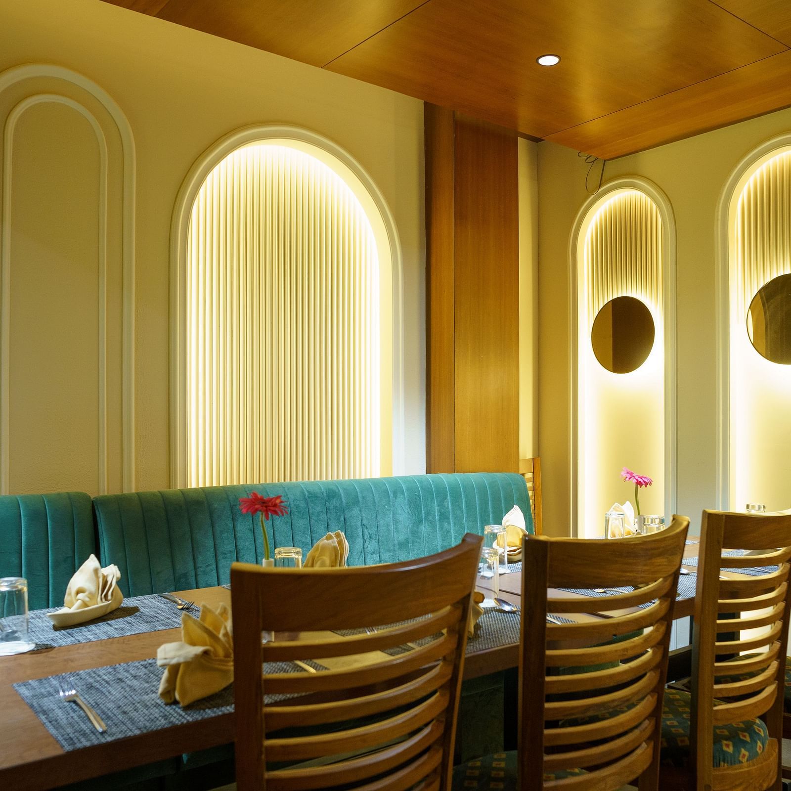 A wide shot of a dining area with booths featuring turquoise upholstery and wooden tables at Orsino Spa Resort.