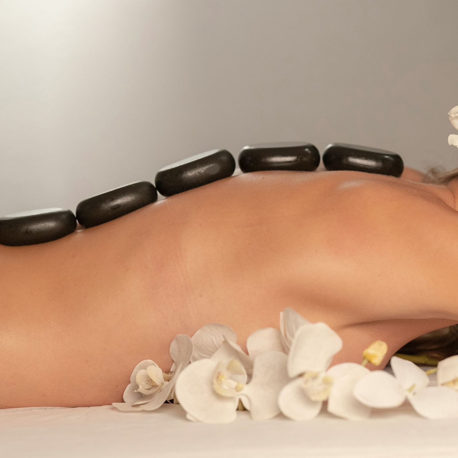 A woman taking a heated stone massage at a spa