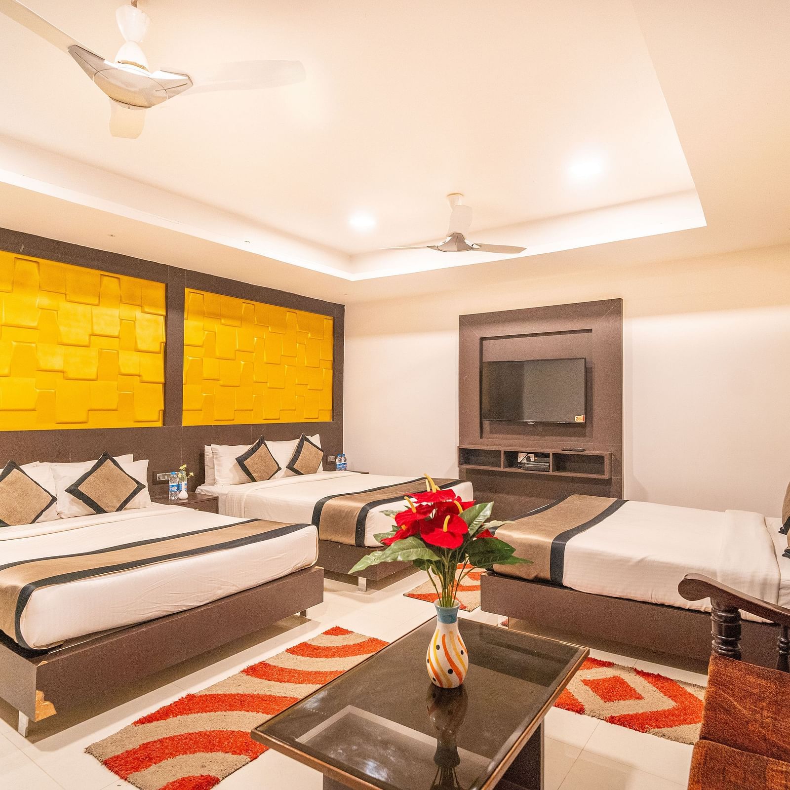 A room with three beds and a sitting area at the side at Parampara Residency, Kushalnagar. 