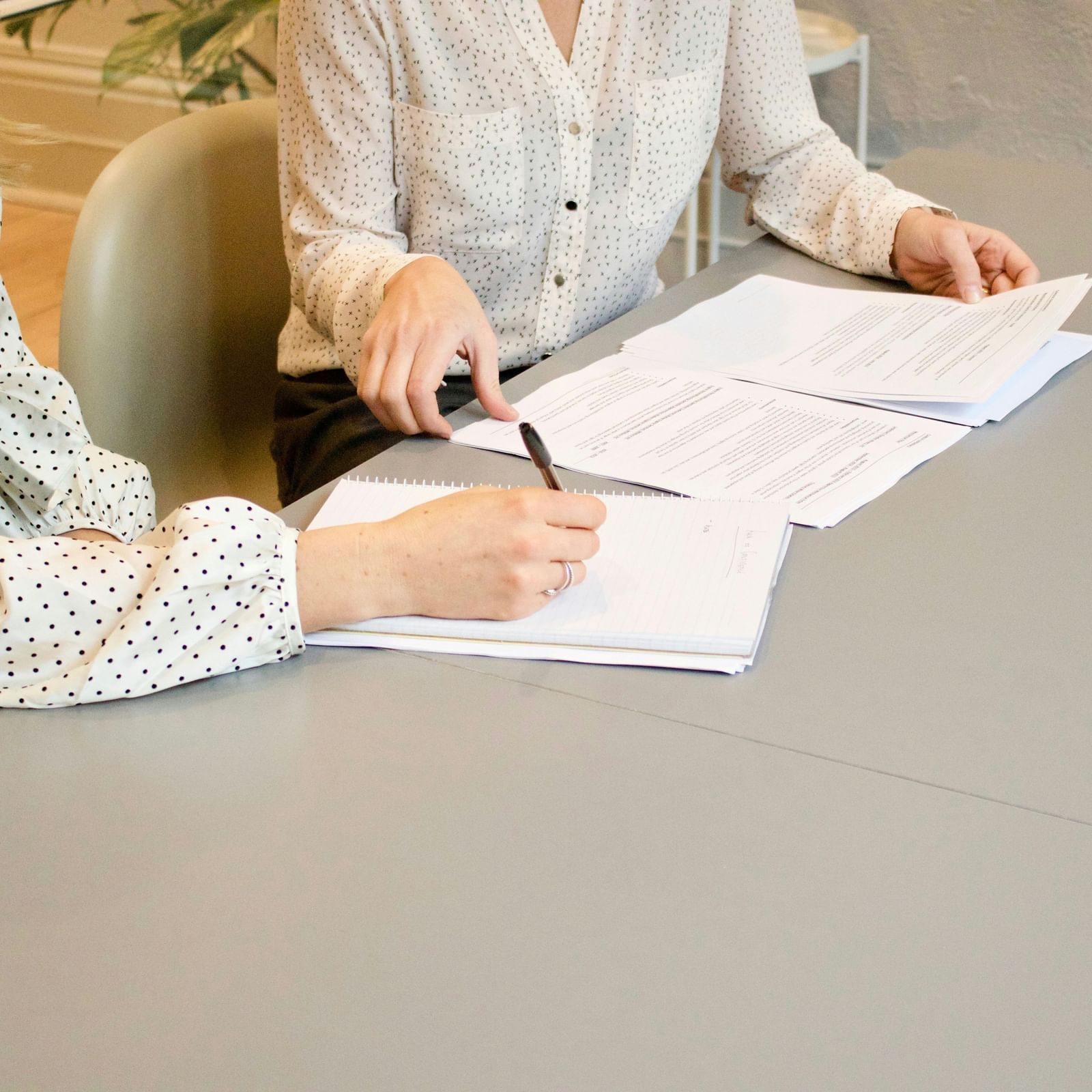 2 people sitting at a table reviewing documents and taking notes.