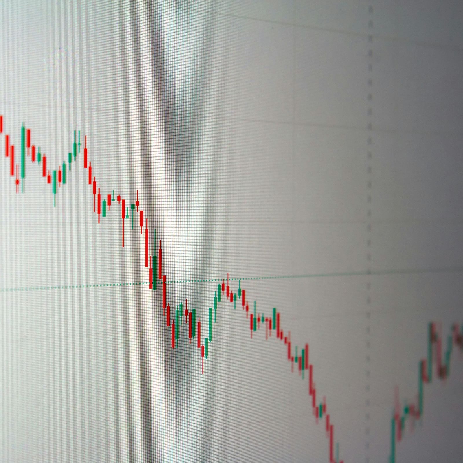 A line chart on a screen showing a downward trend in stock prices with red and green indicators.