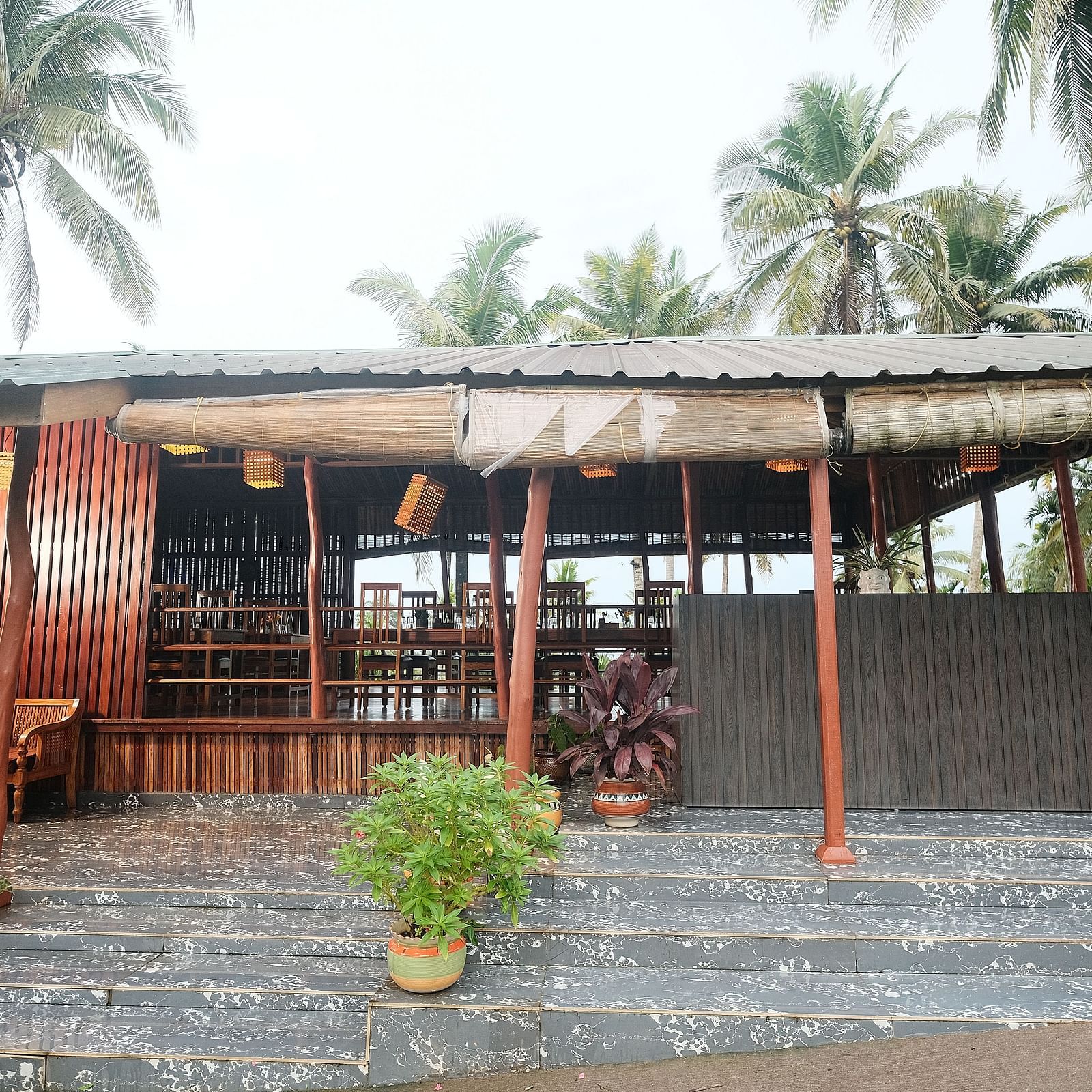 The exterior of a restaurant with a garden area, showing the outdoor seating and surrounding greenery | Fusion Cafe and Multi-cuisine | RainForest Resort, Port Blair, Andaman and Nicobar Island