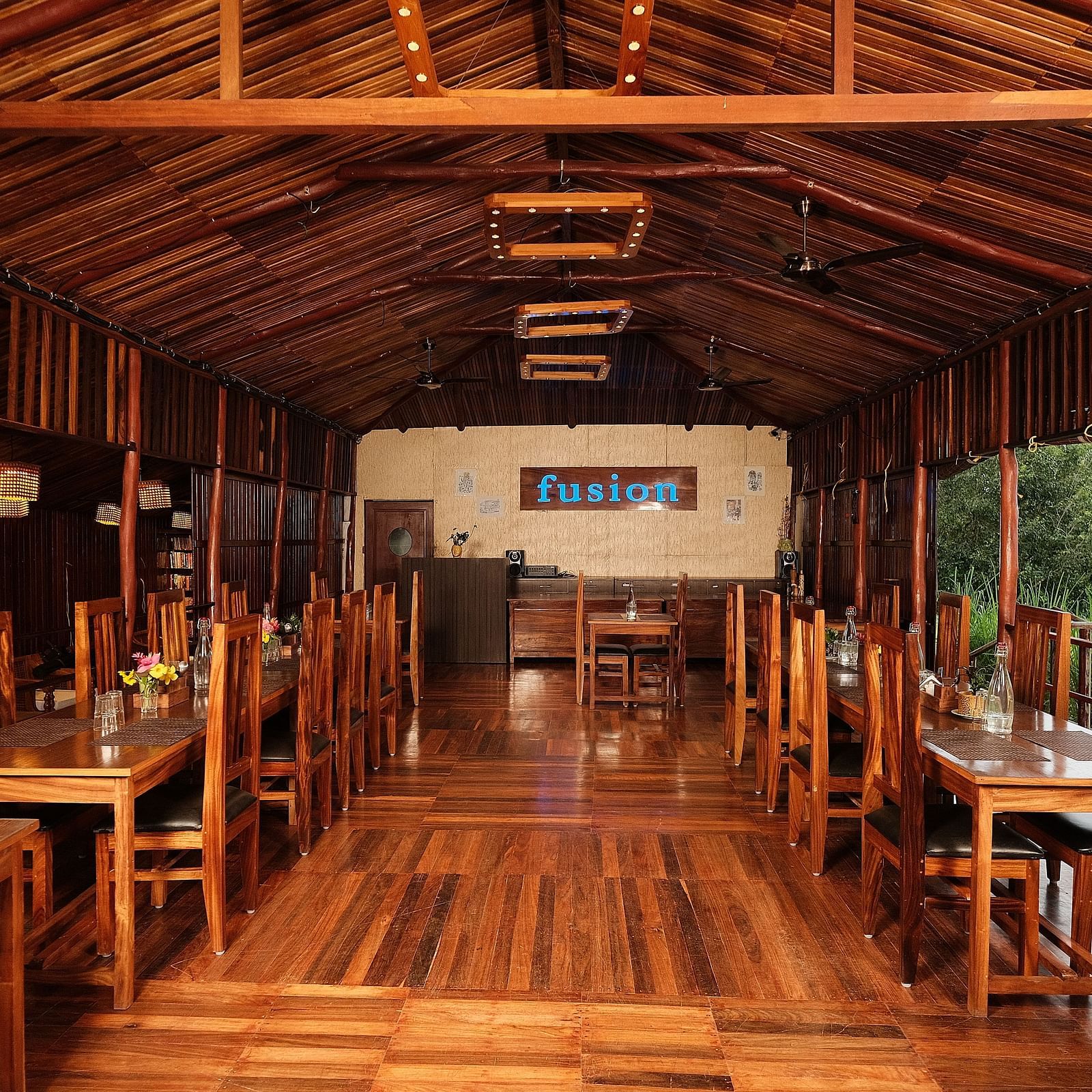 The interior of a wooden restaurant with tables and chairs | Fusion Cafe and Multi-cuisine | RainForest Resort, Port Blair, Andaman and Nicobar Island