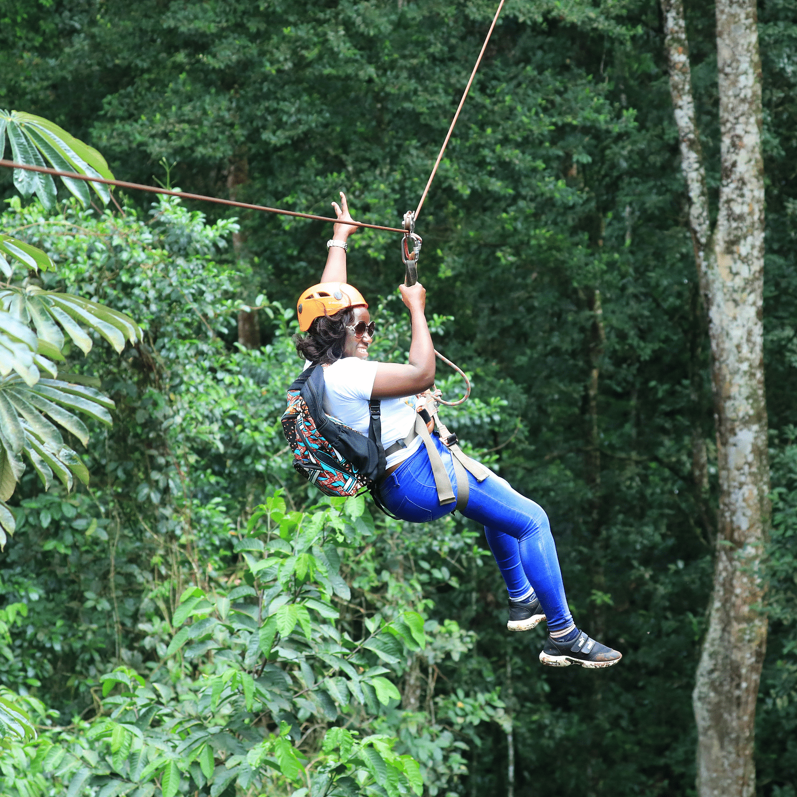 Image of a woman enjoying zip lining with a background of lush trees 
