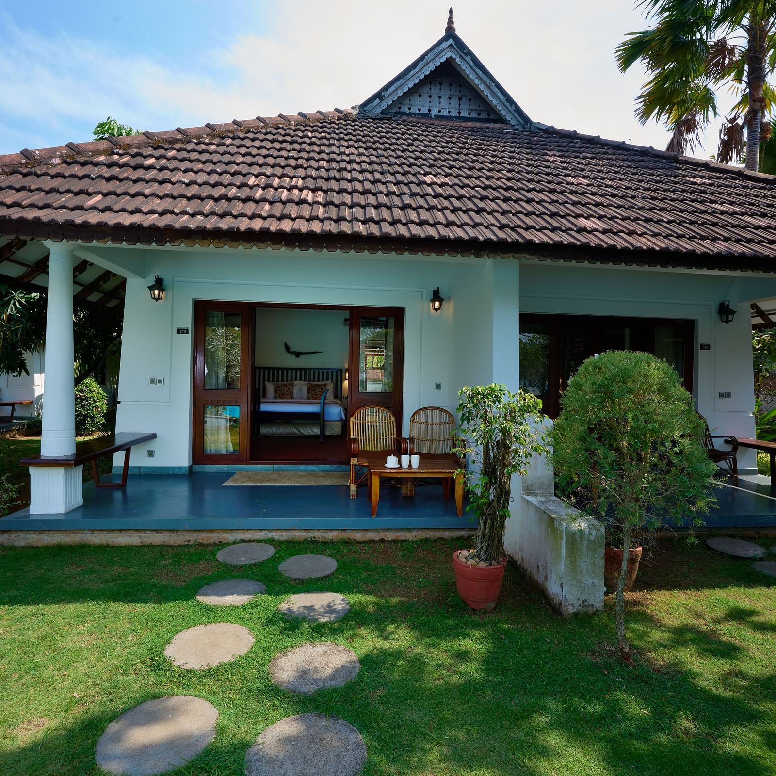 An image of a cottage surrounded by lush green lawn - Rhythm Kumarakom