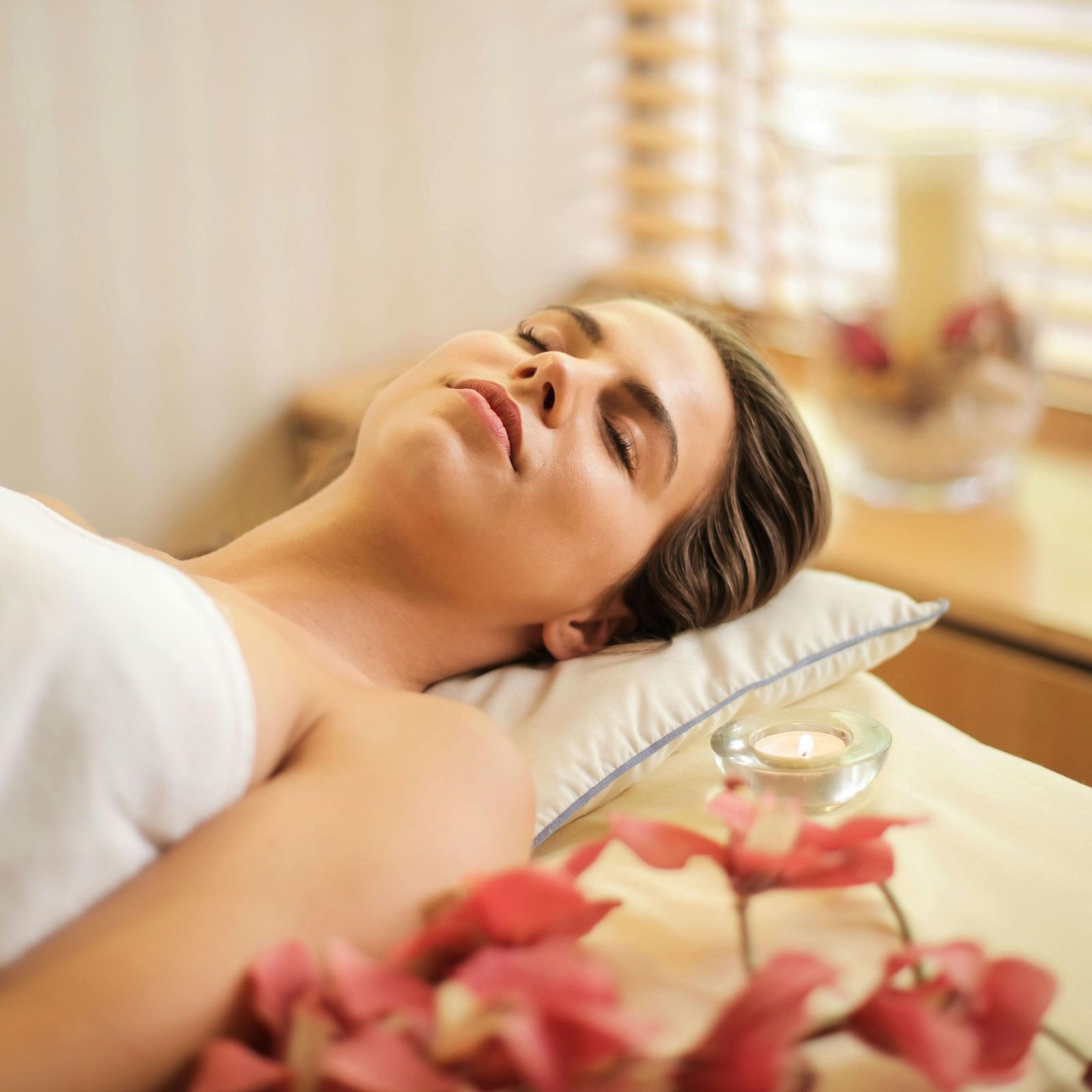 A lady lying on the bed, ready for a spa treatment, with flower petals in the foreground