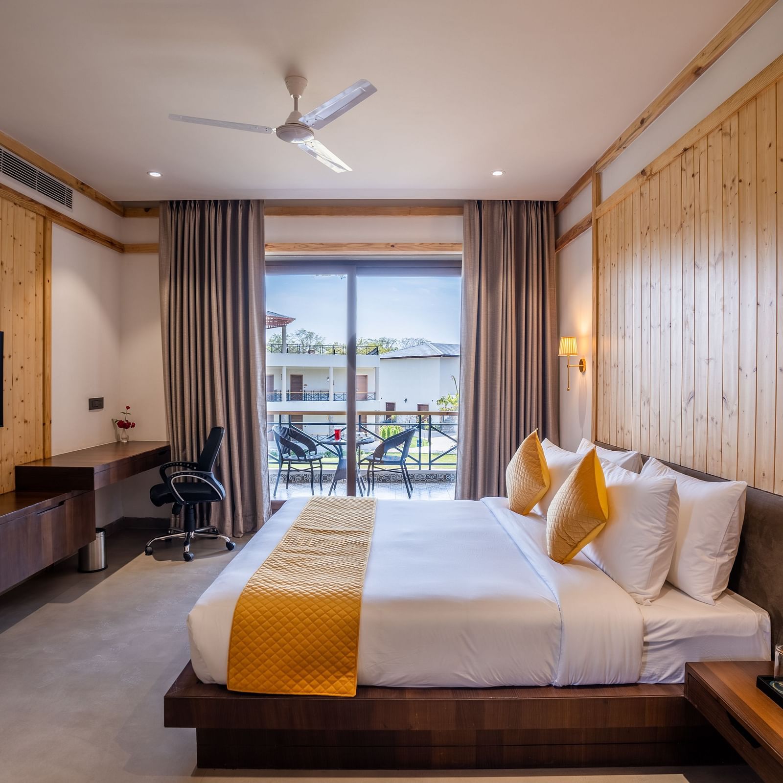 A superior room with a large bed, a wall mounted television, a balcony and ambient lighting - Shervani Pebbles & Pines, Corbett
