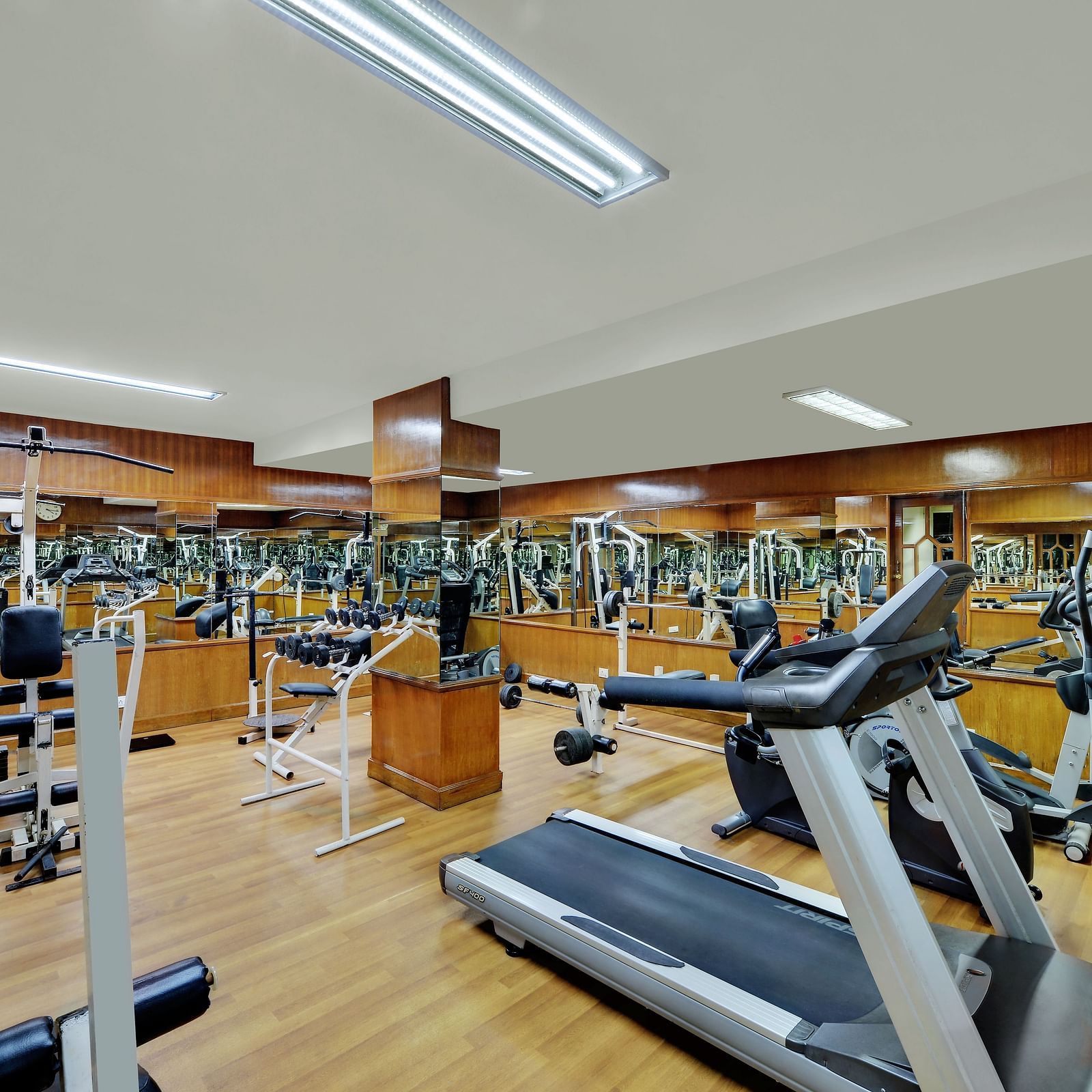 All equipped gym at Side angle shot of restaurant with wooden furnished table and chairs at SRM Hotel Maram Malai Nagar, Chennai