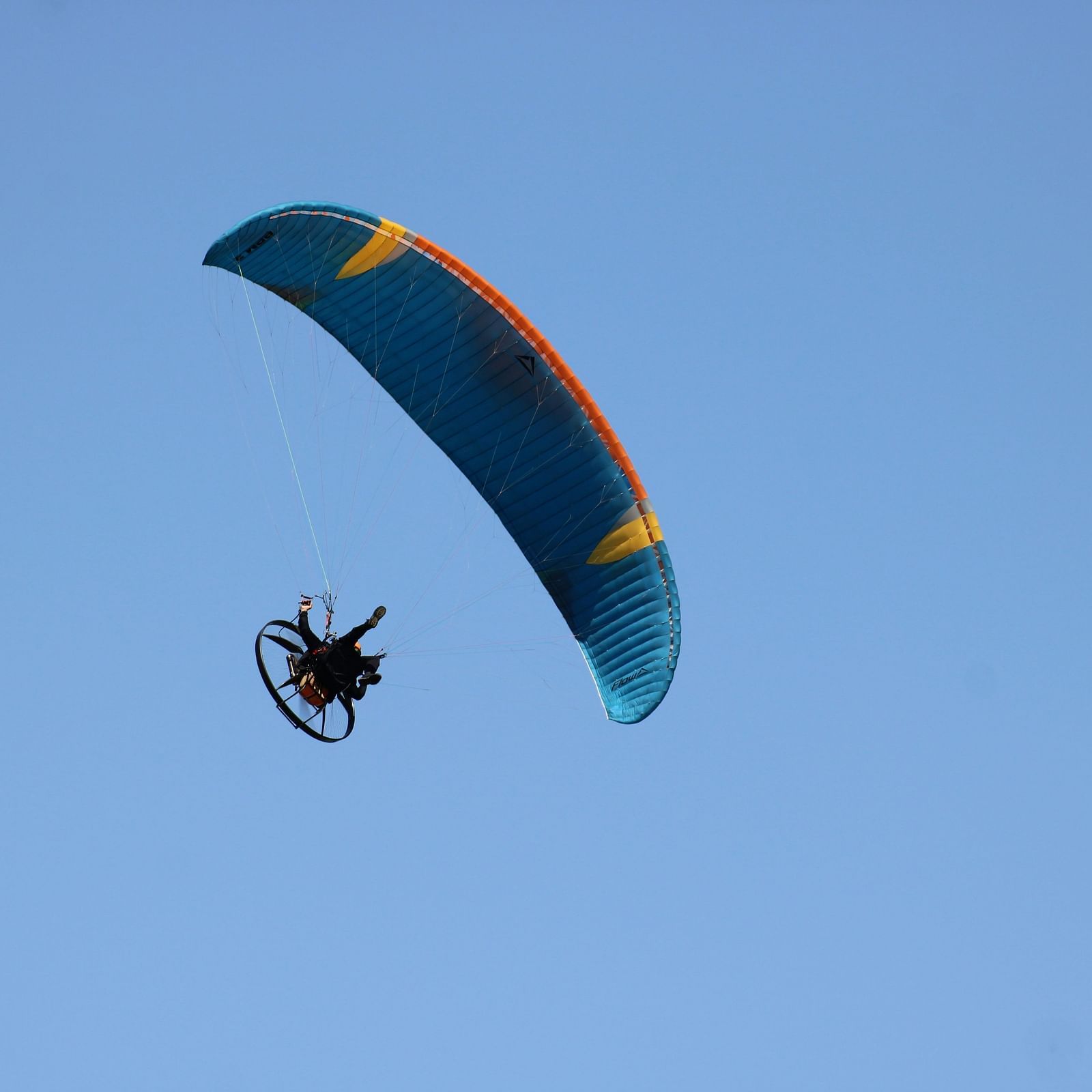 Paraglider soaring high above a hilly landscape.