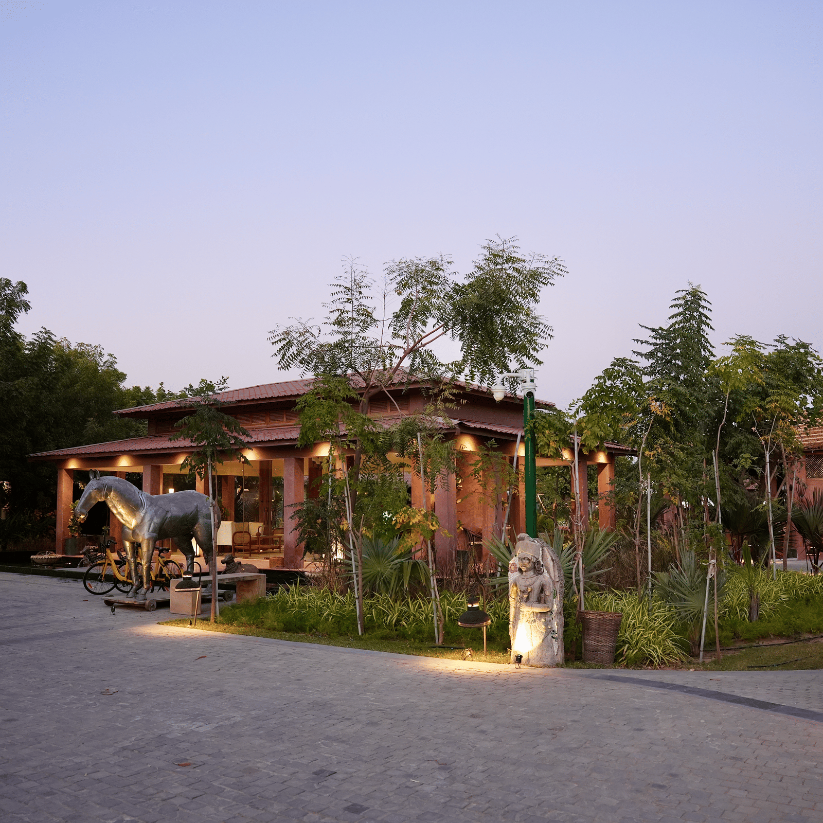 Facade of Surpura Bagh with trees surrounding it and a pathway leading to the reception under evening sky