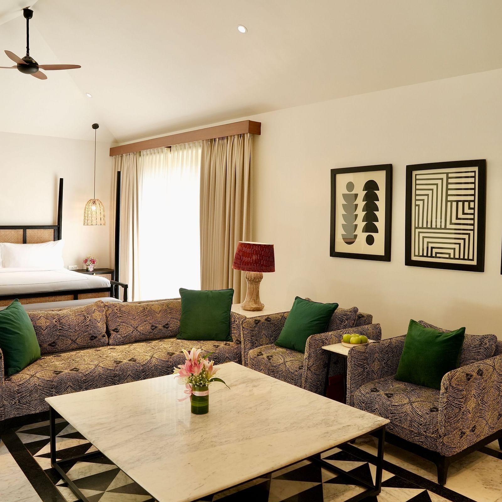 A room with a bed and a seating area adorned with frames at Surpura Bagh.