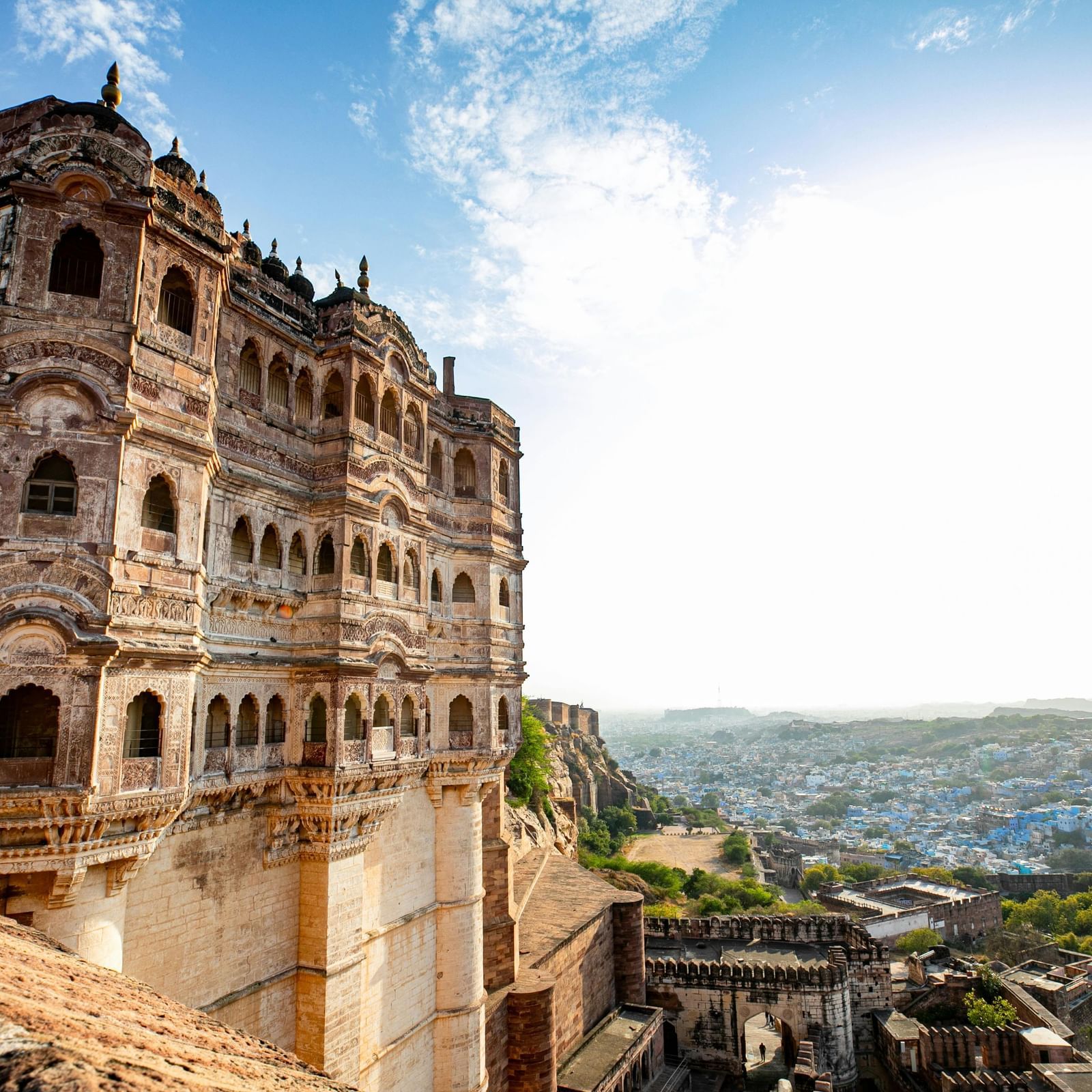 Ancient stone fort bathed in golden sunset light, with lush greenery in the foreground and colorful clouds in the sky.