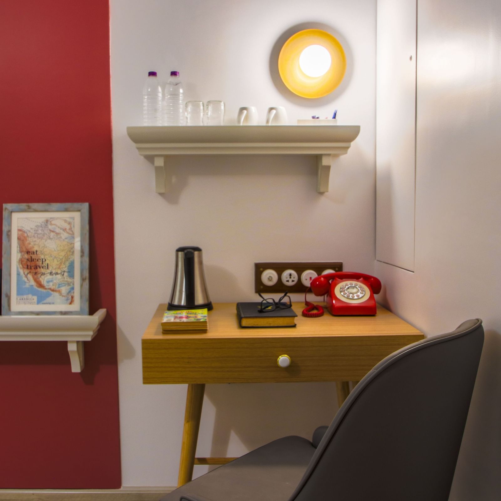 A small wooden desk with a drawer, a red phone, and a lamp in the room  | T24 Retro