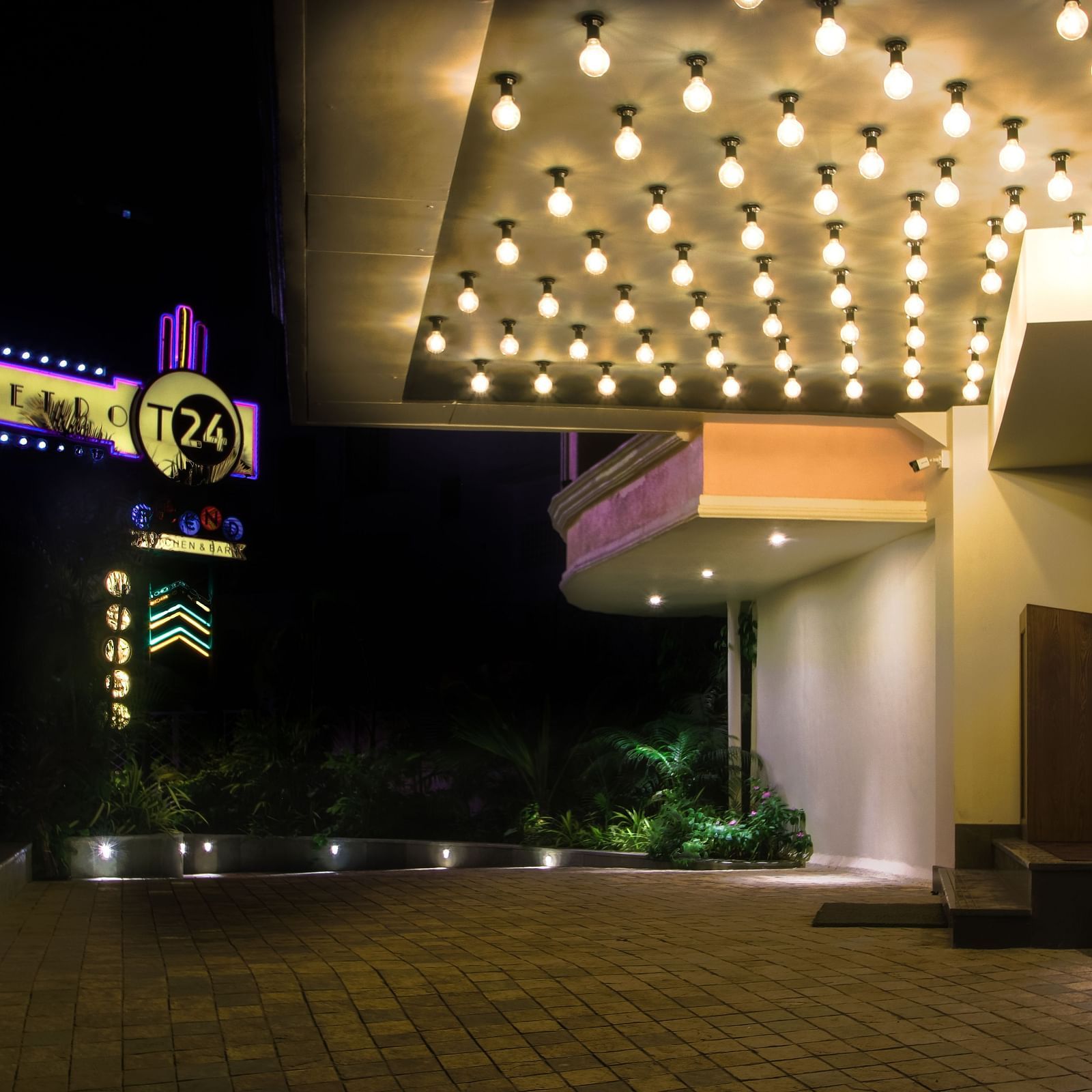 A well-lit entrance to a building with a unique sign and a ceiling full of lights.