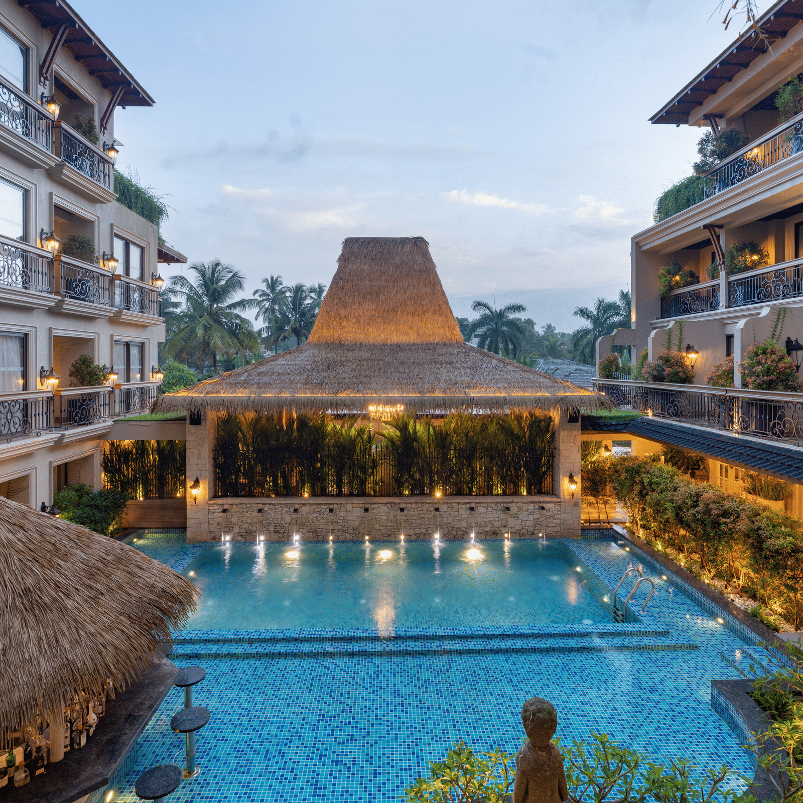 The swimming pool at The Evren, Vagator, between 2 building complexes during the early evening hours.