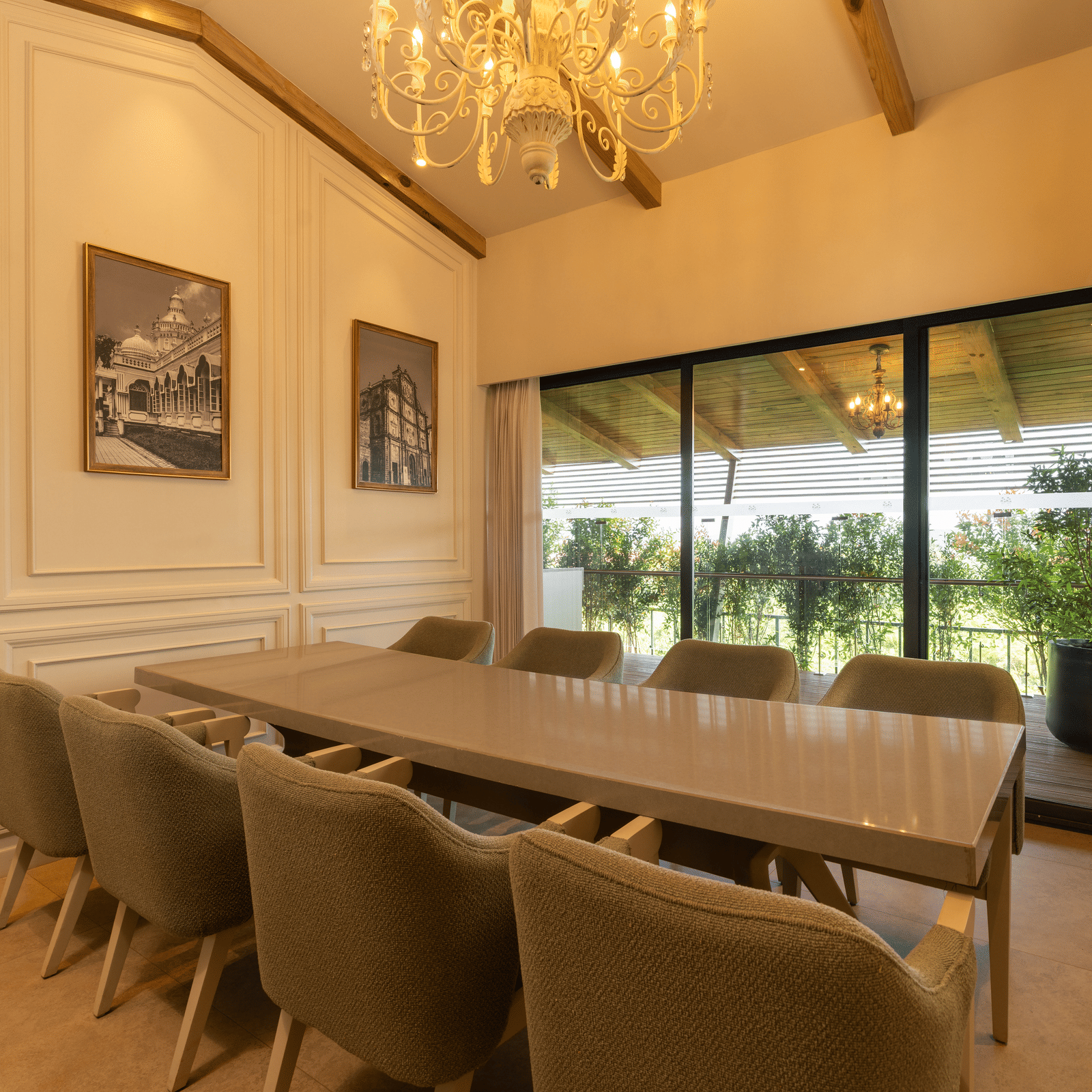 A brightly-lit boardroom at The Evren, Vagator, featuring a long conference table with a window behind it overlooking the lush green lawns.