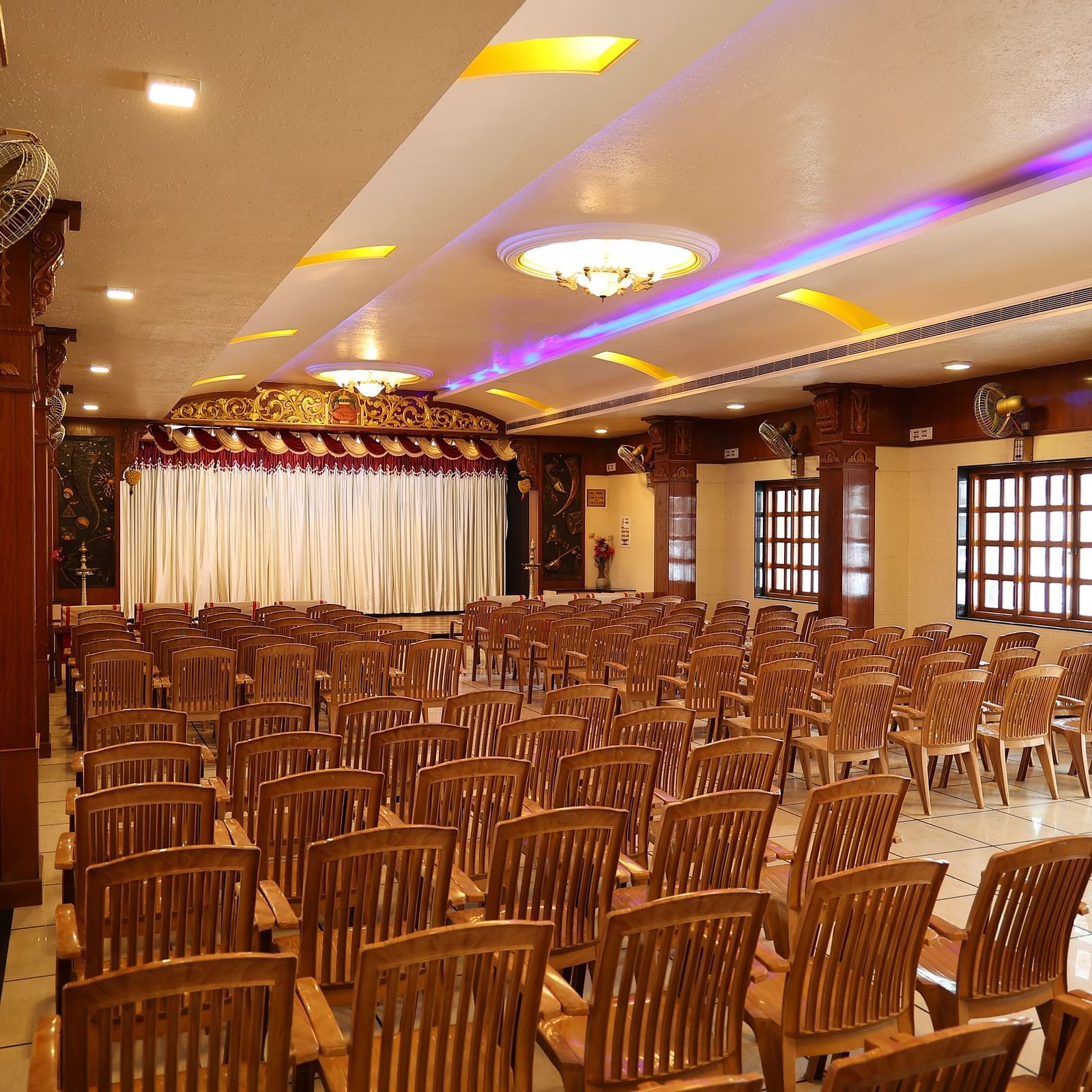corner view image of the banquet hall with a lot of brown coloured chairs arranged at The Grand Krishna Rooms