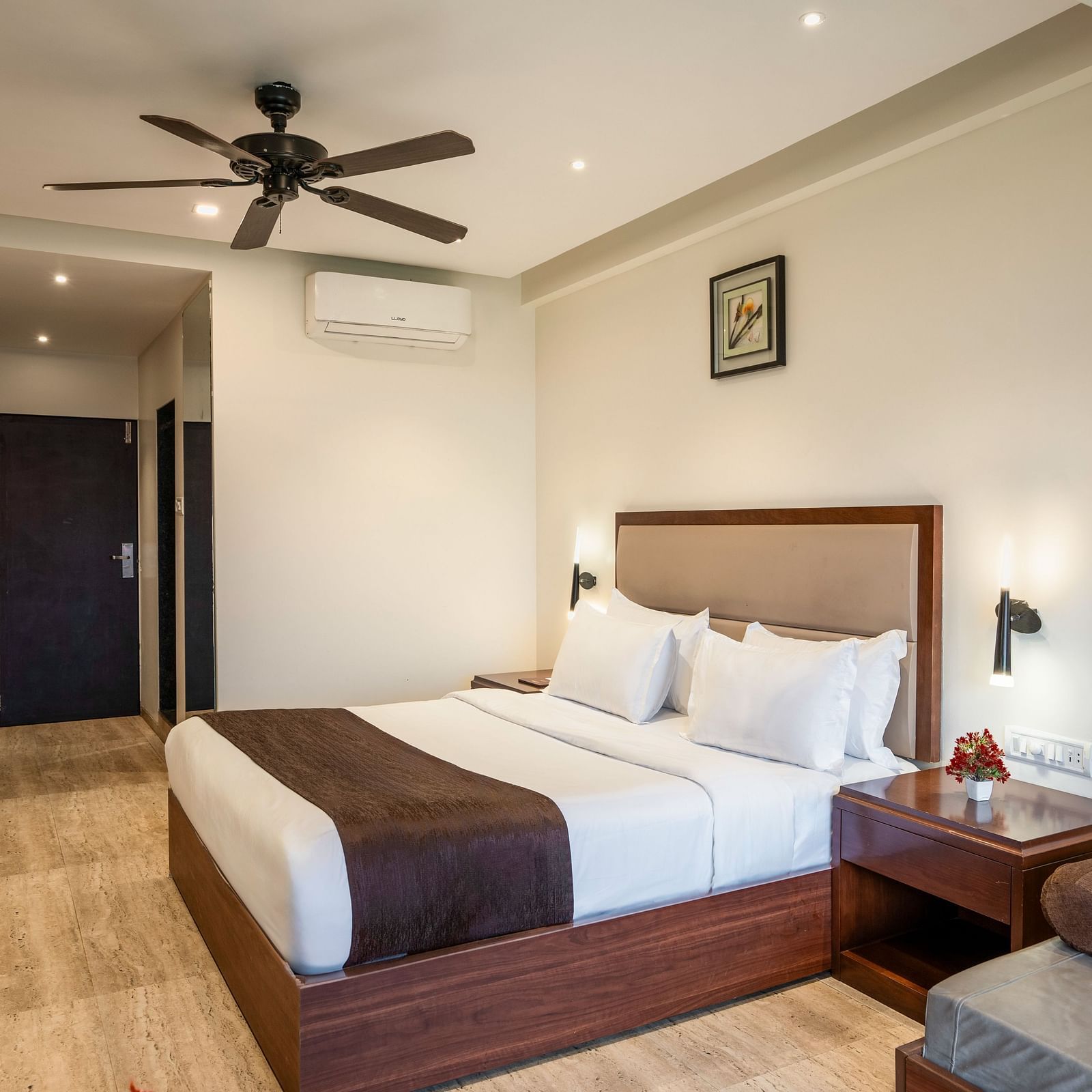 Shot of a comfortable room at our resort featuring a king size bed, side table, a couch | Shot of the facade of the resort clicked from the lush green lawn during a cloudy day | The Grand Legacy Resort and Spa