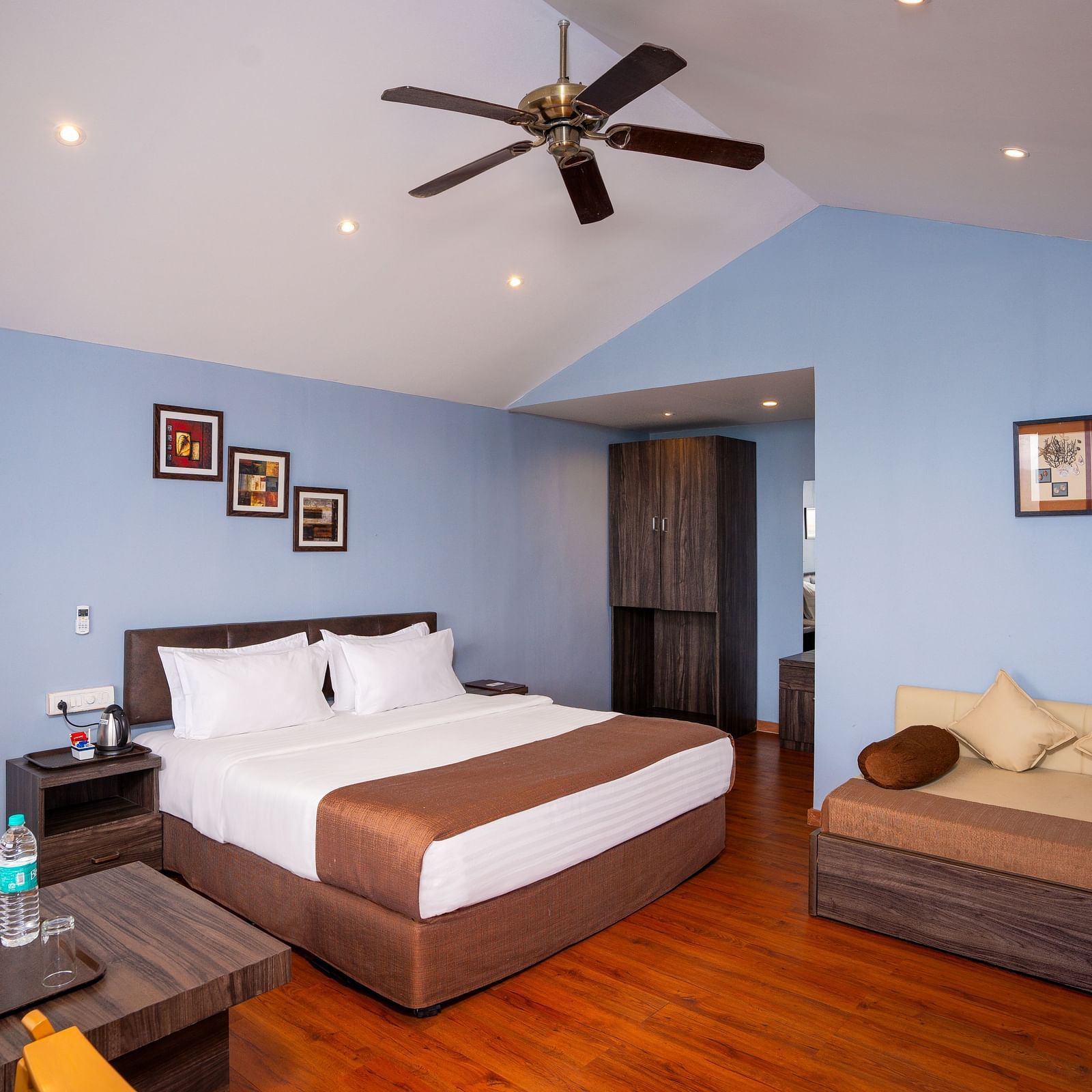 A image of a spacious room with a king size bed and a couch along with several  wall decors | The Grand Legacy Resort and Spa