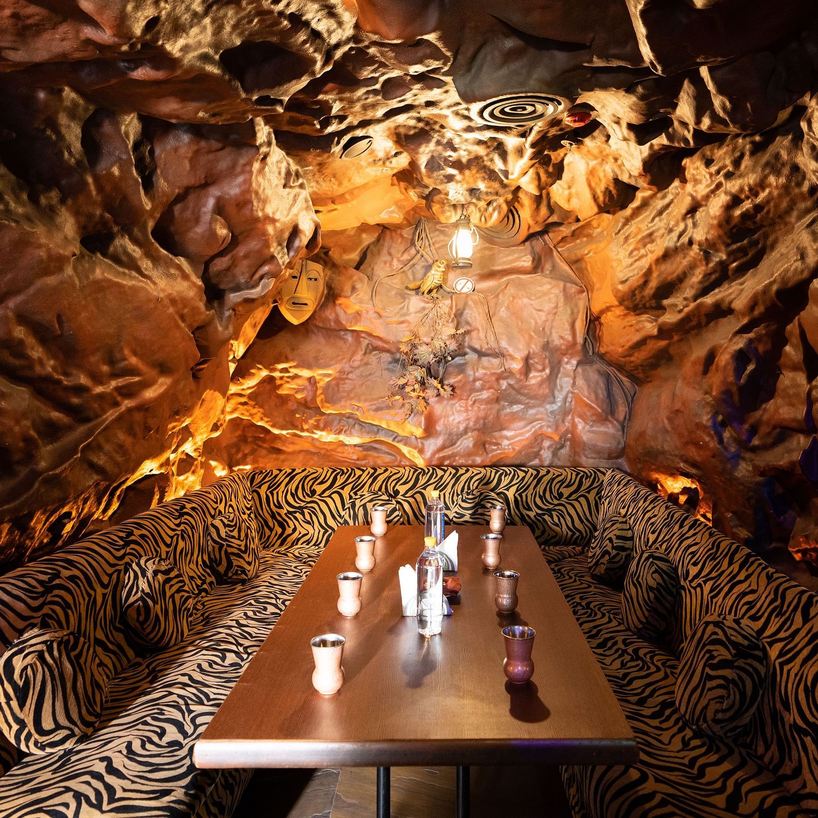 A unique restaurant with a cavernous atmosphere featuring a large Buddha face sculpture and textured walls, creating an immersive dining experience - The President Hotel Jayanagar, Bangalore