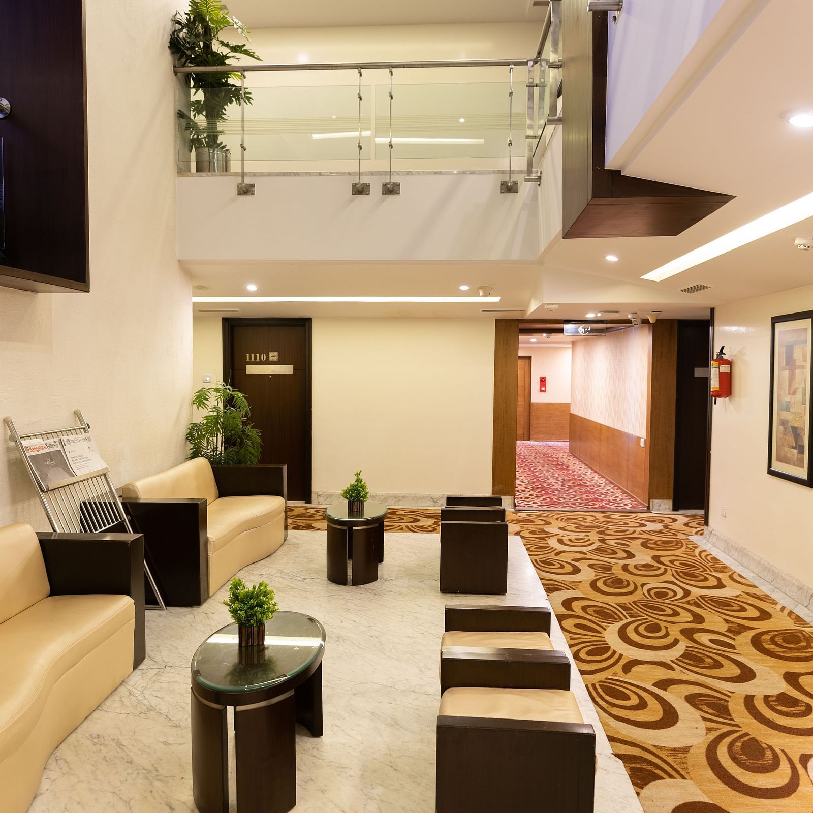 A modern hotel lobby area with comfortable seating, decorative plants, and contemporary art under a bright and welcoming atrium - The President Hotel Jayanagar, Bangalore