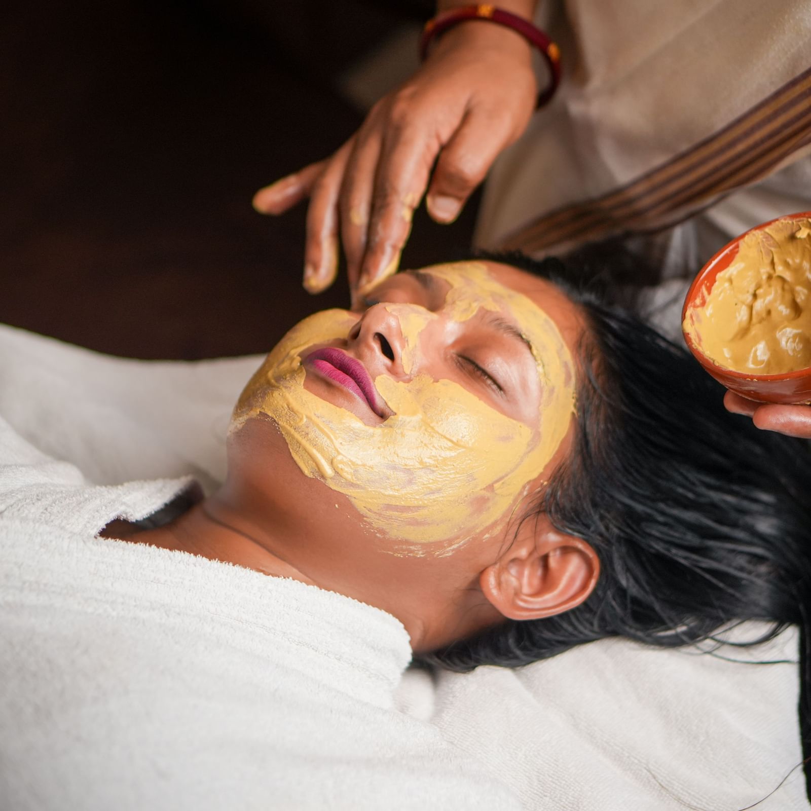 Facial mask application in Vedic Village Spa Resort, featuring a person receiving a natural face pack.