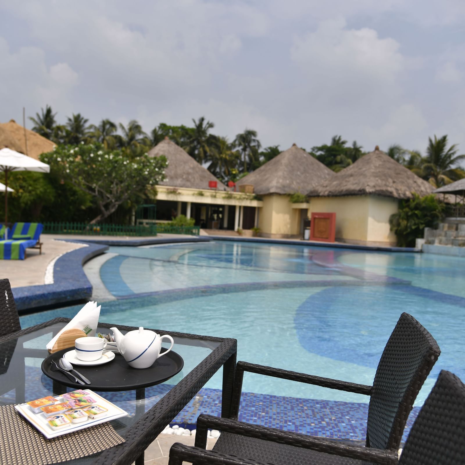 A table with food and drinks next to a swimming pool at Vedic Village Spa Resort.