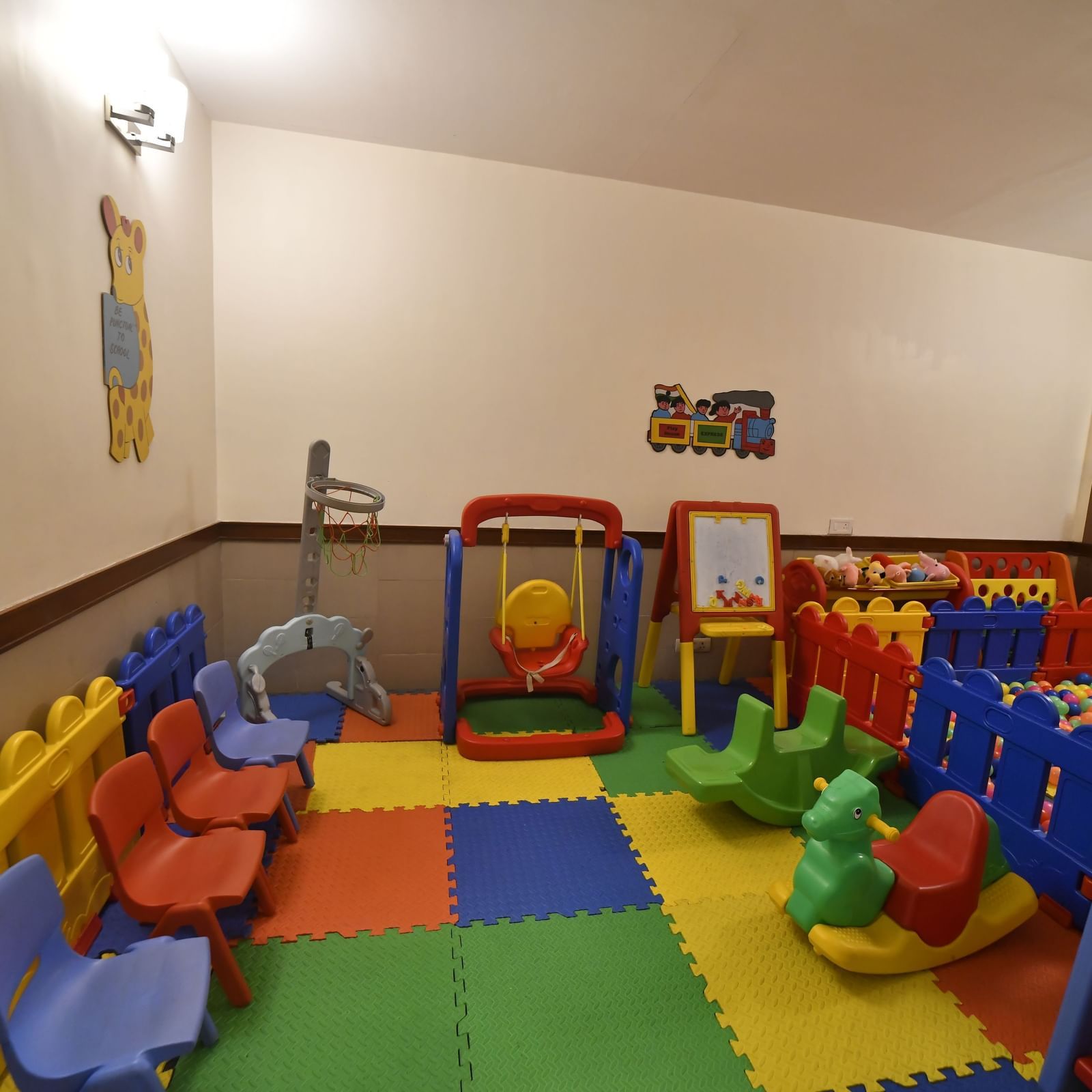 A colourful indoor play area is filled with various plastic toys and soft mats