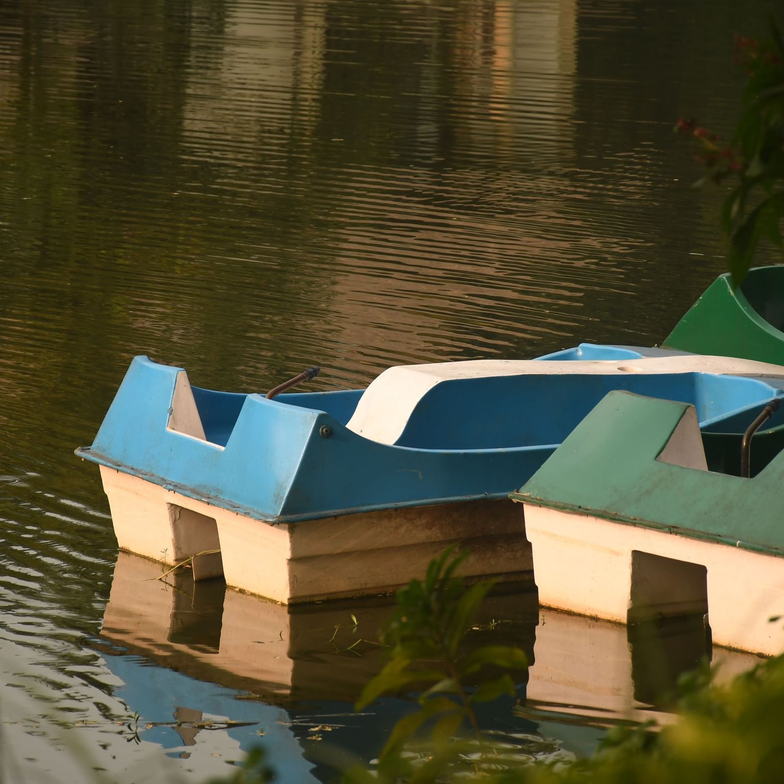 Multiple blue and white paddle boats partially submerged in a body of water
