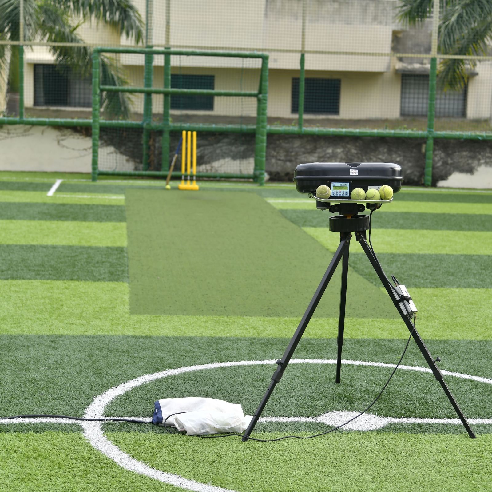 A tripod-mounted camera setup on a green artificial turf sports field