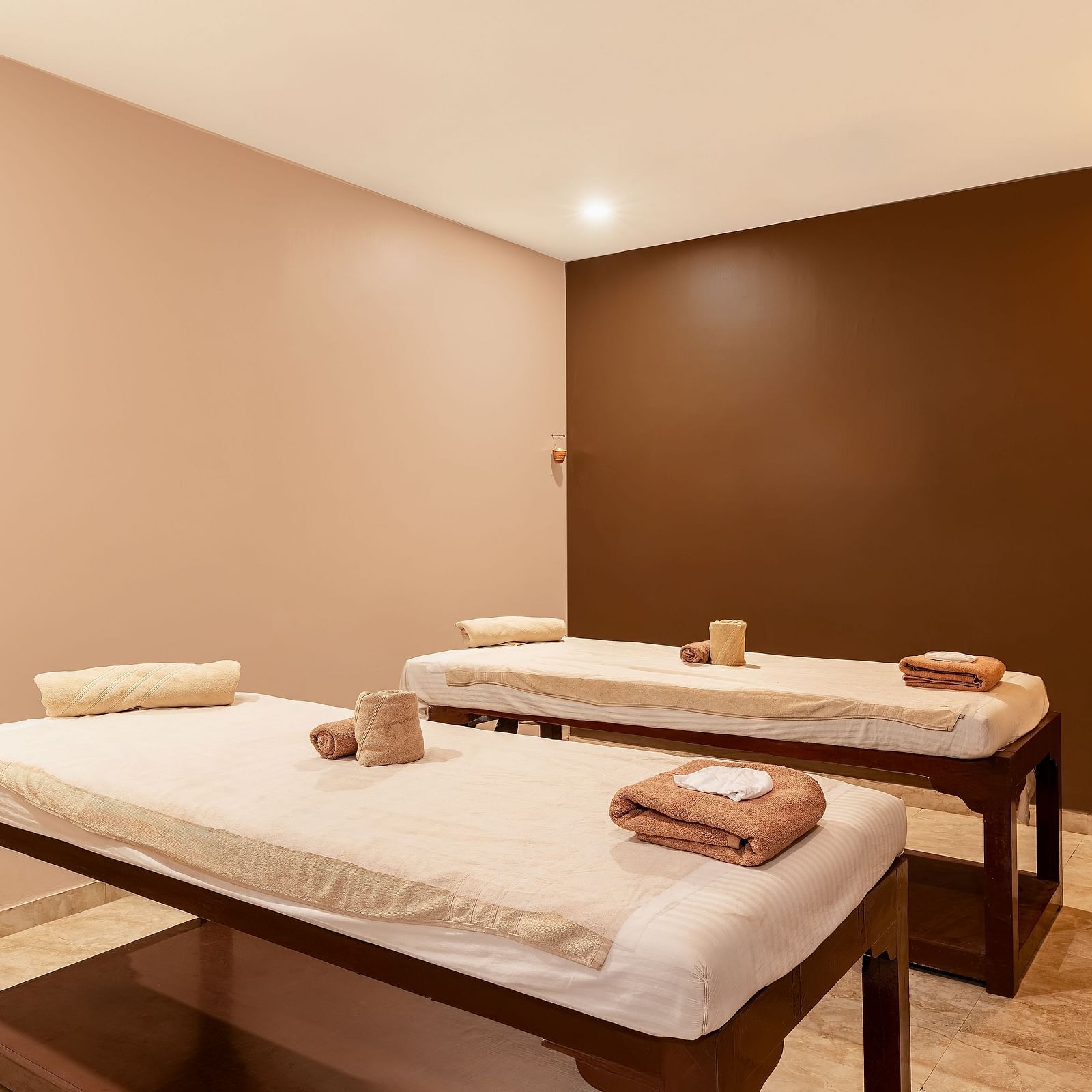 A spa room with two massage tables, towels, and a warm, inviting atmosphere - Via Lakhela Resort & Spa, Kumbhalgarh