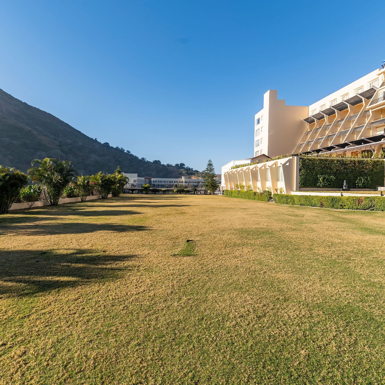 A wide shot of a building with a mountain backdrop - Via Lakhela Resort & Spa