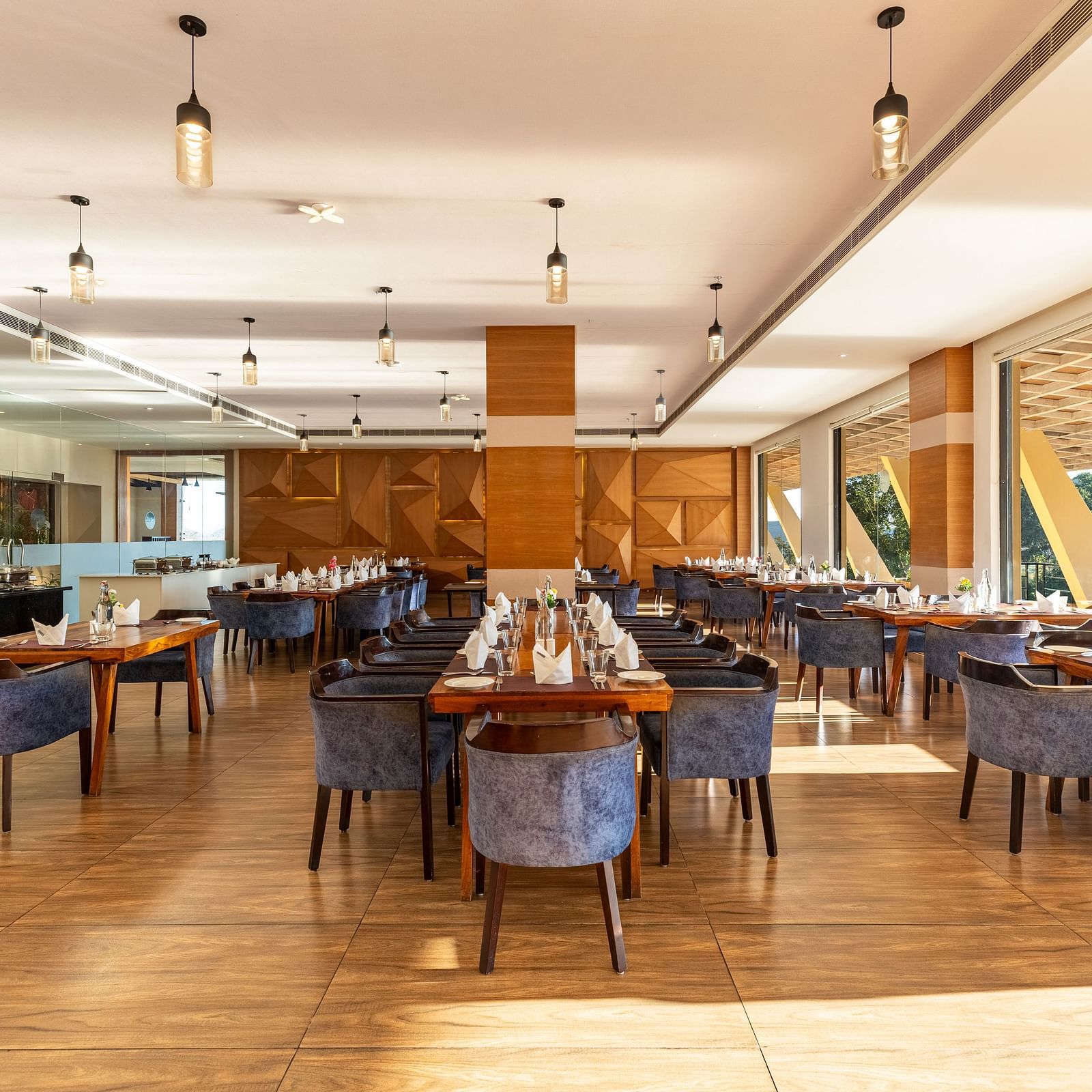 Restaurant interior with tables, chairs, and large windows under a warm lighting - 