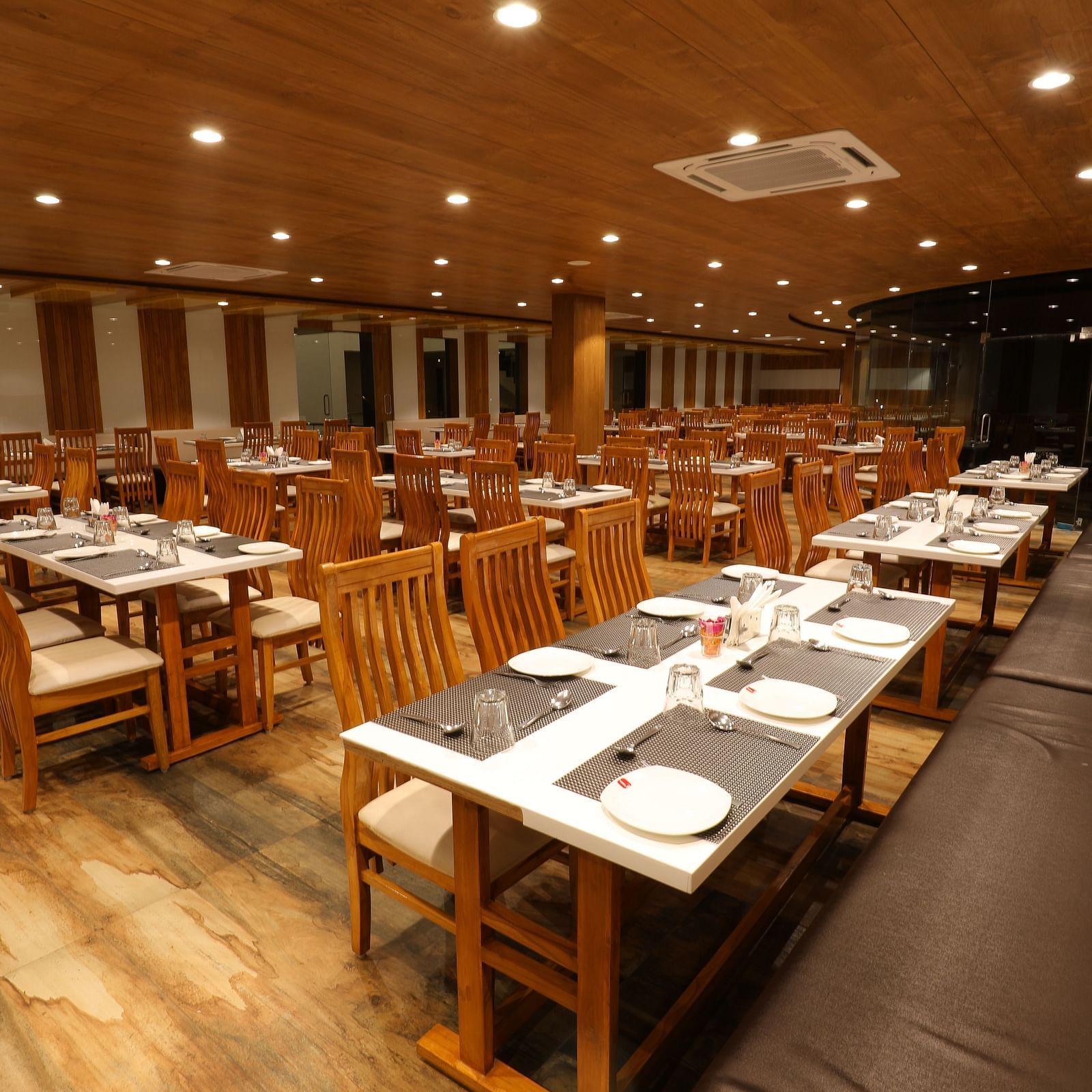 Warmly lit interiors of the Blue Coriander Restaurant with various seating arrangements at Vishal Lords Inn Gir Forest