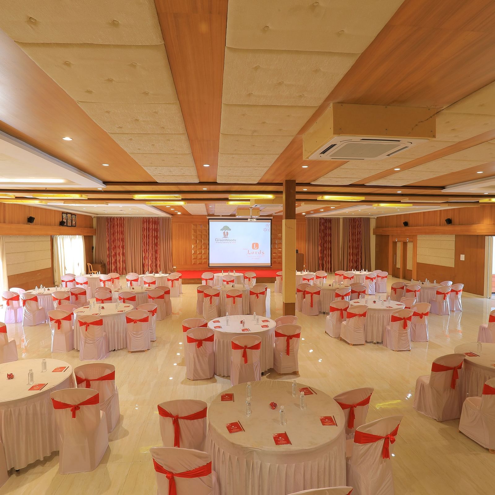 A large banquet hall in cluster seating arrangement with round tables, ready for an event at Vishal Lords Inn Gir Forest