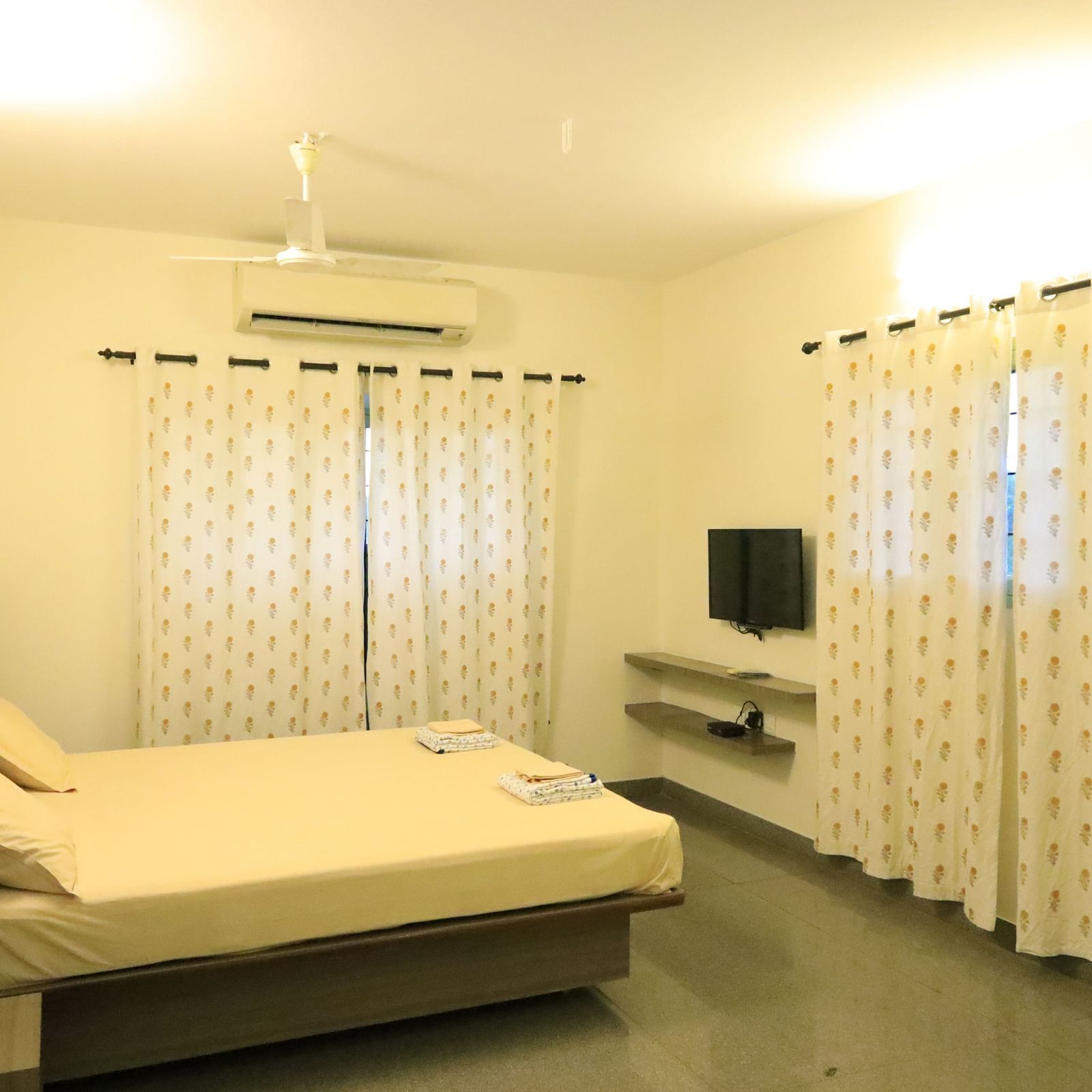 A room at Wyt Hotels Transit Nest, Madurai featuring a double bed, curtains covering windows, and a flat TV screen.