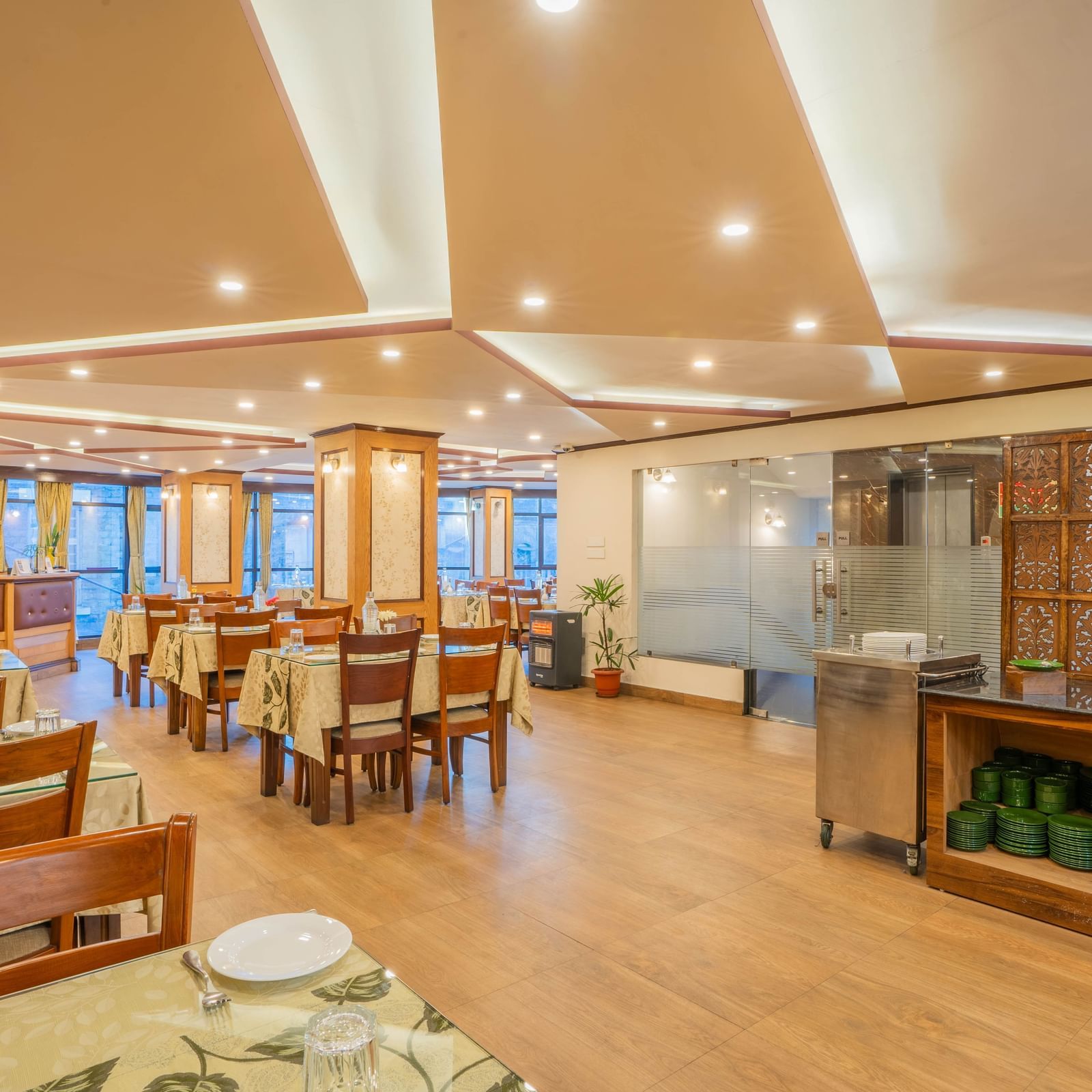 A bright and spacious hotel restaurant with tables, chairs, and a buffet counter at the Yashshree Jai Hotel & Banquet, Darjeeling.
