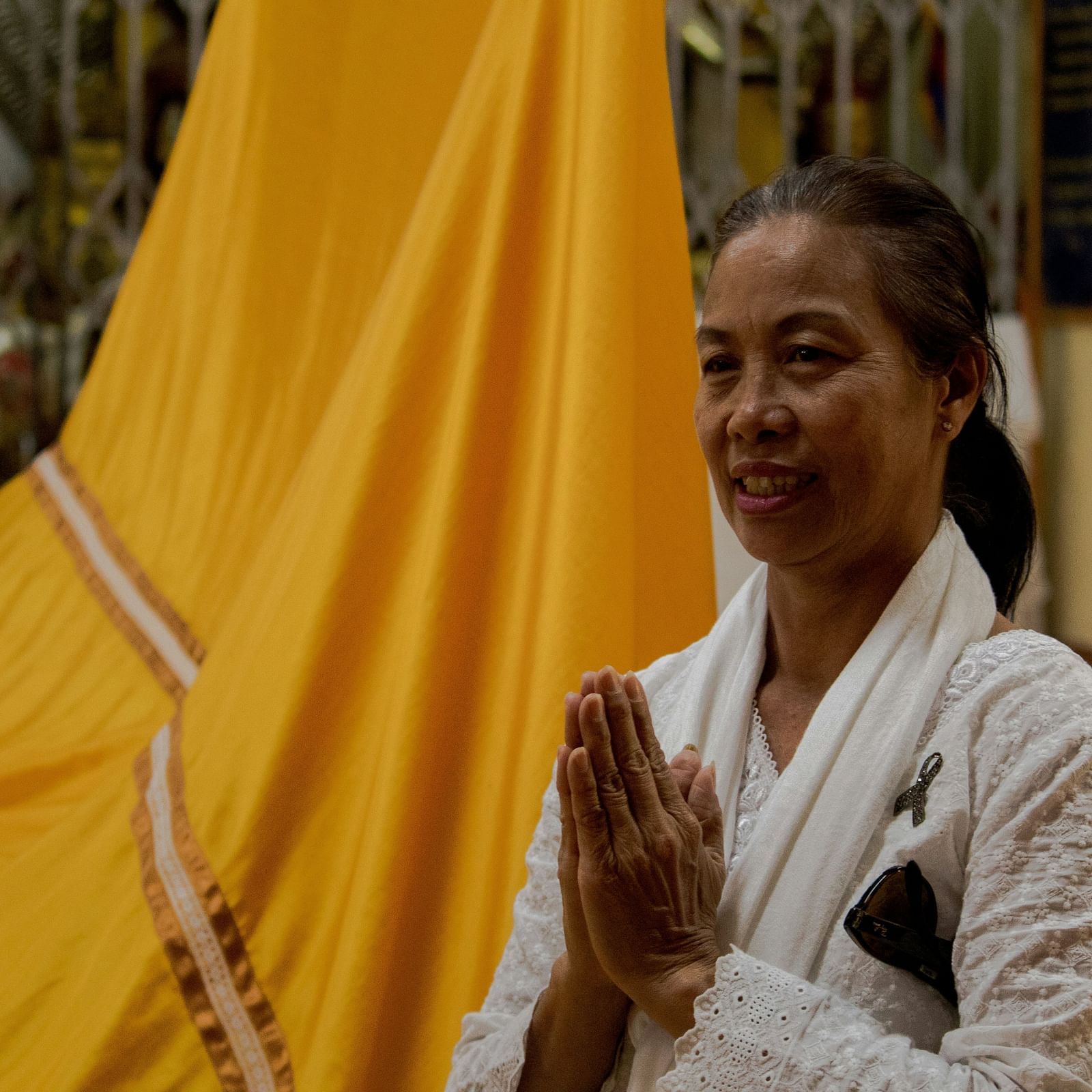 an image of a woman joining her hands in prayer with a yellow cloth in the background