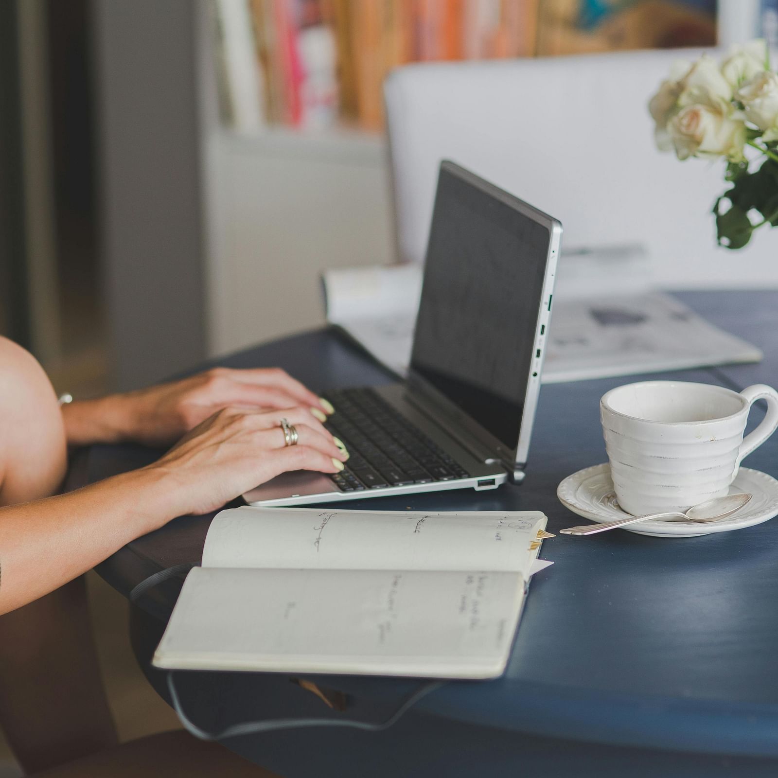 image of a person working on their laptop with an open notebook kept beside it