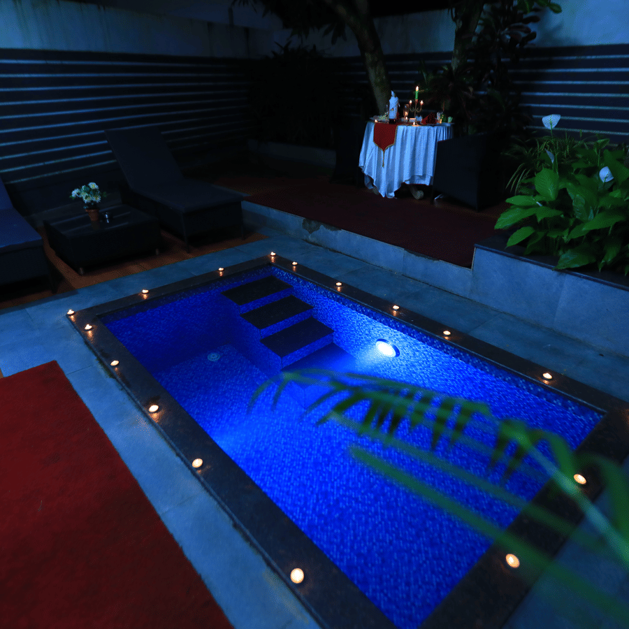 Image of a swimming pool at night with lights on the sides of the pool at Parampara Resort & Spa, Kudige, Coorg.