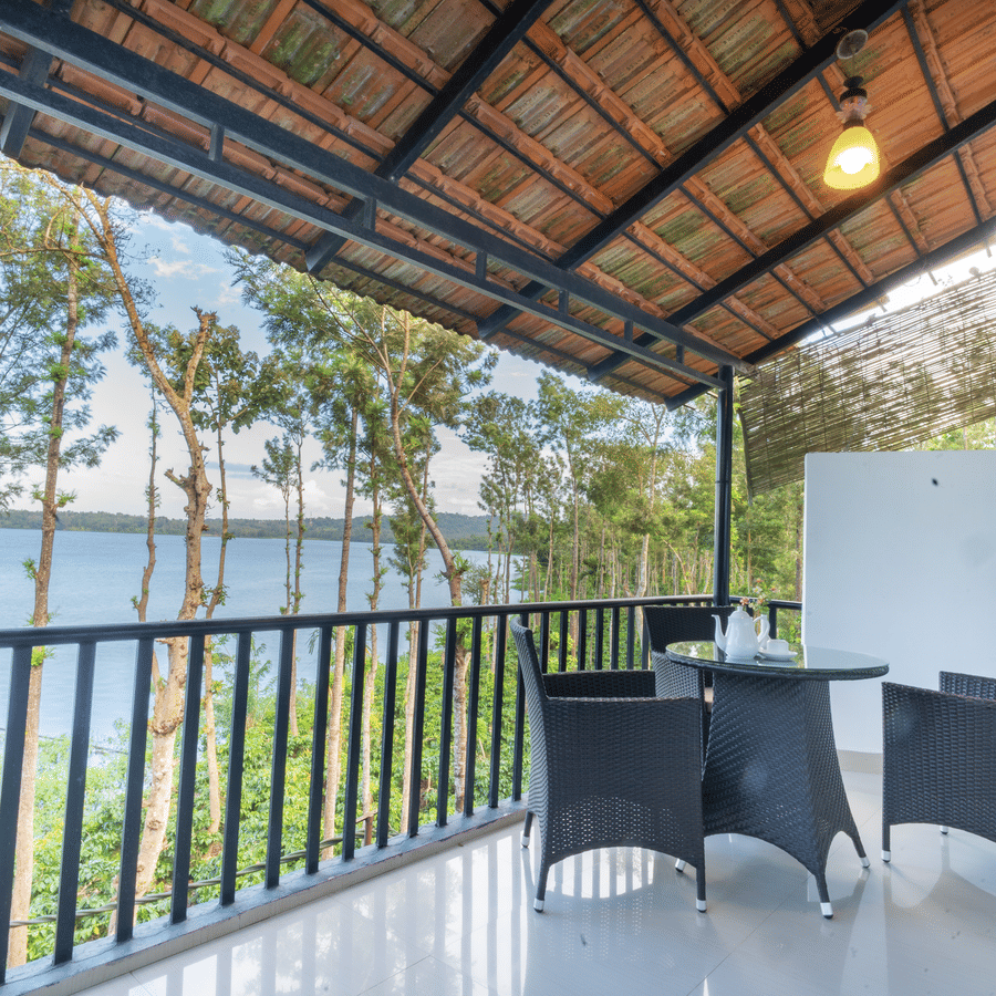 Image of a seating area with chairs and a table with a view of the nature around it at Coorg Jungle Camp Backwater Resort, Kushalnagar.