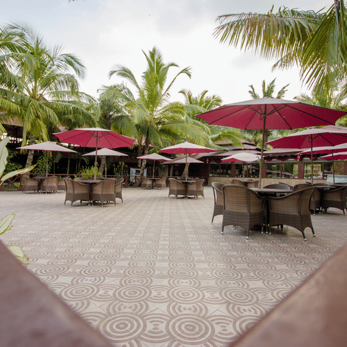 Outdoor seating area of Buddha Garden, offering delectable seafood in Havelock, featuring wicker chairs, garden umbrellas, and surrounding coconut trees.