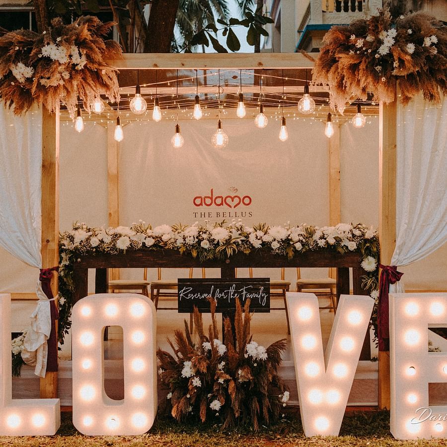An image of a beautifully decorated space with flowers and lighting, featuring illuminated love letters and a sign that reads Reserved for Family.